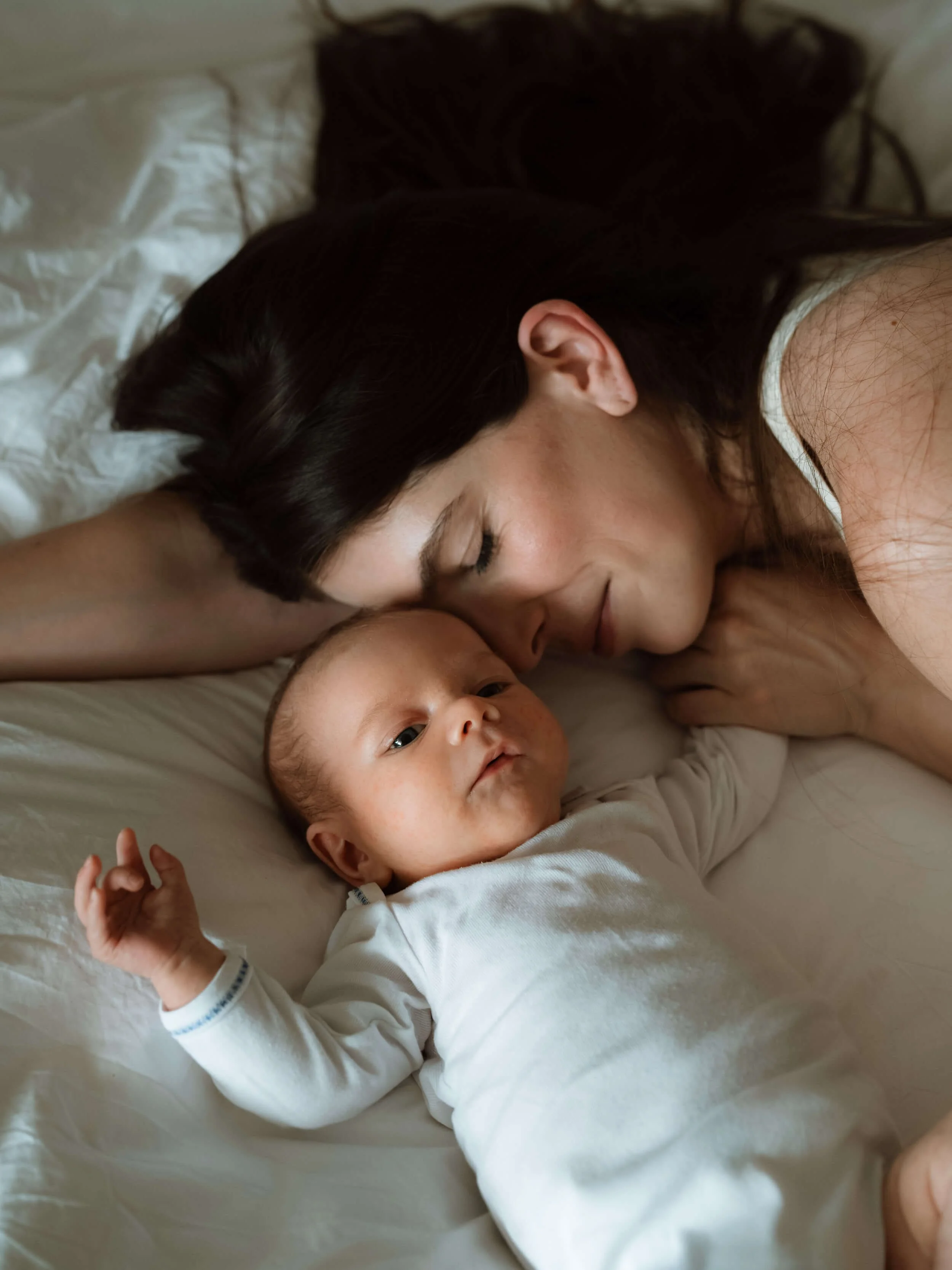 Mama i beba leže na krevetu tijekom profesionalnog fotografiranja kod kuće