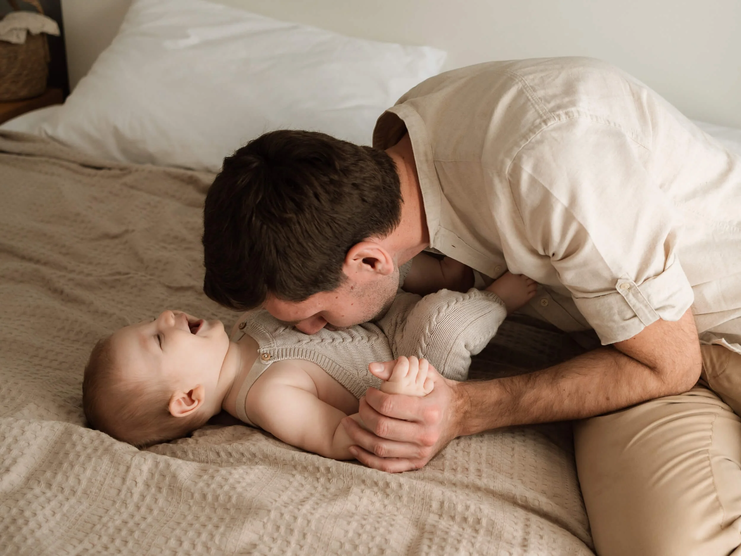 Tata se igra sa bebom doma na krevetu