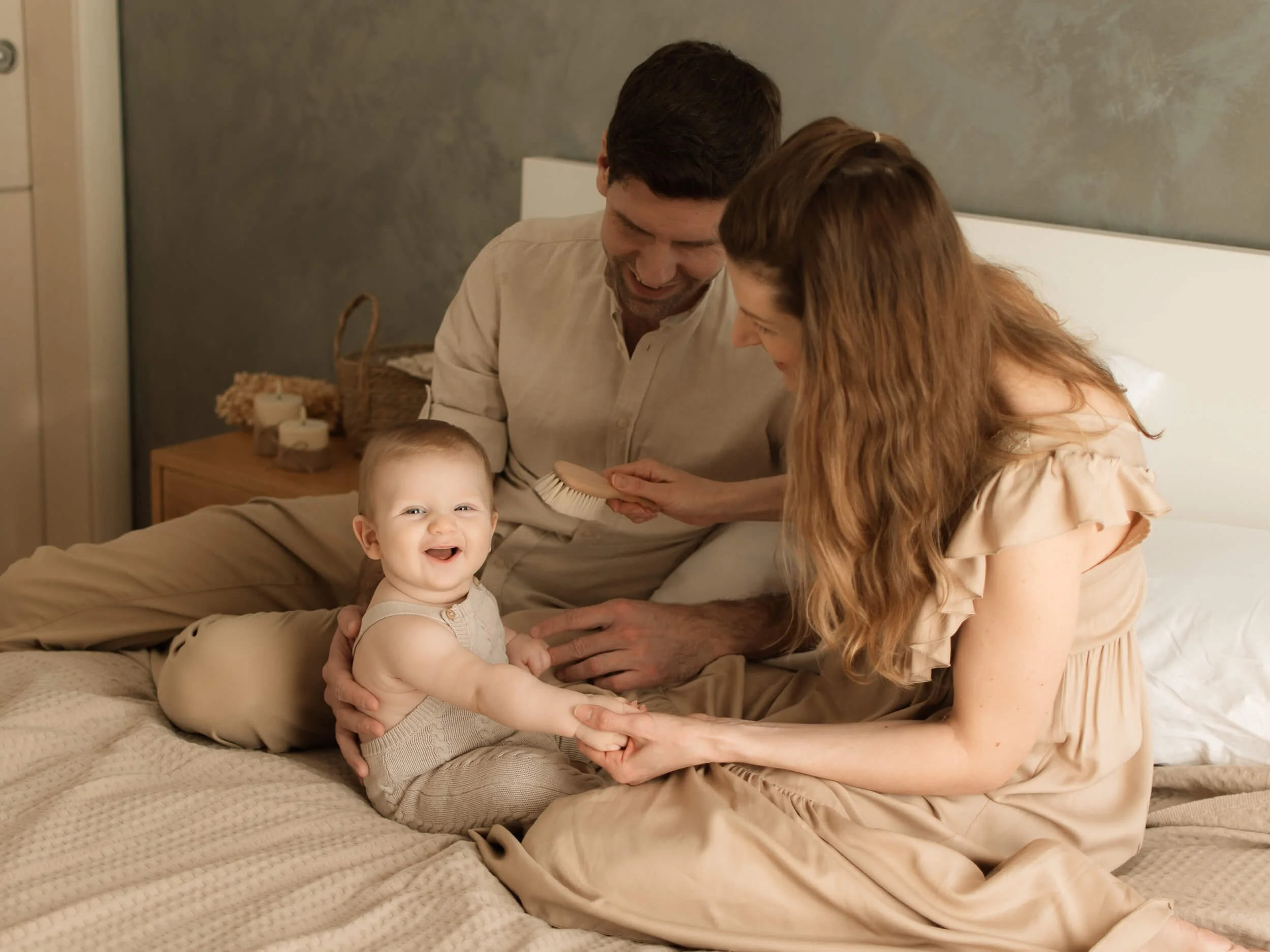 Roditelji i nasmijana beba na krevetu