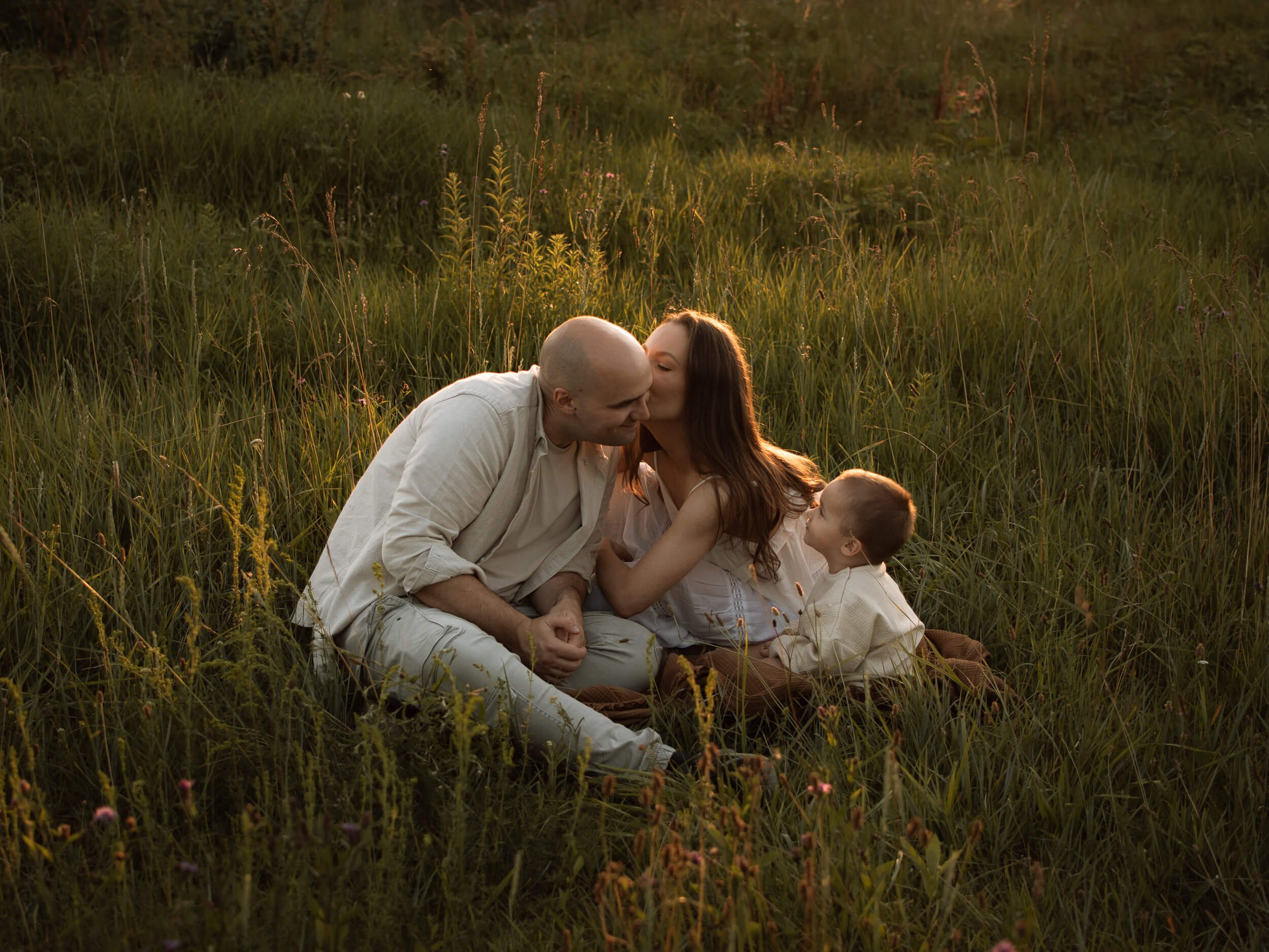 Obitelj sjedi u travi, profesionalno obiteljsko fotografiranje u prirodi