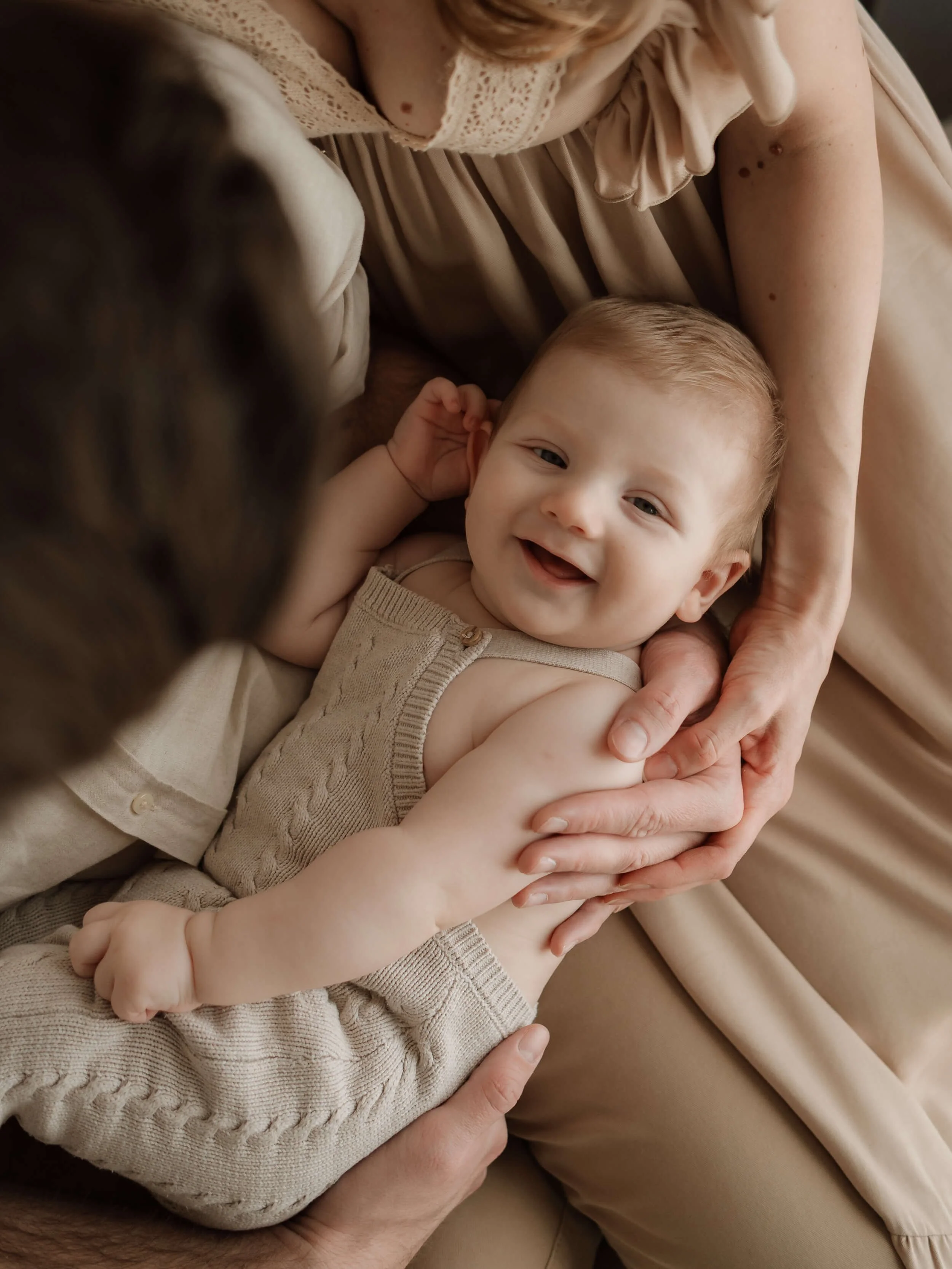 Nasmijana beba u naručju roditelja