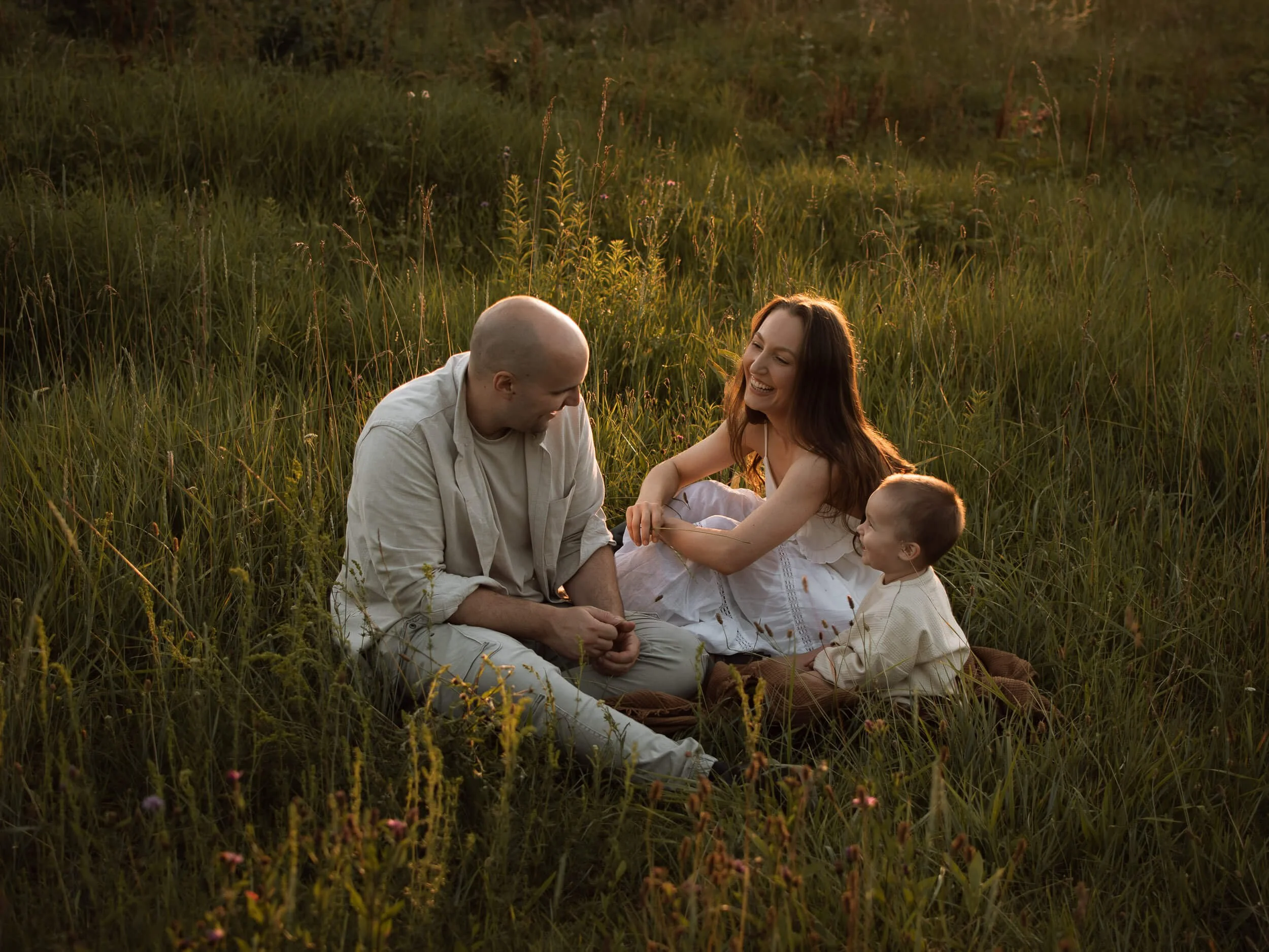 Fotografiranje obitelji u prirodi, nasmijana obitelj sjedi u travi