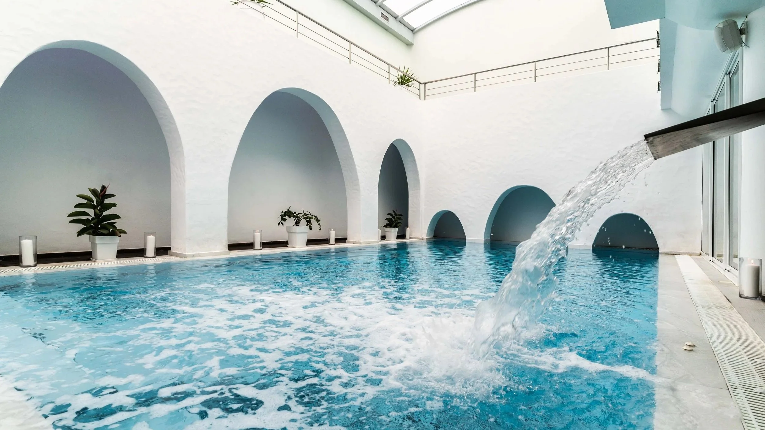 Indoor pool area with water fountain and arch ways.