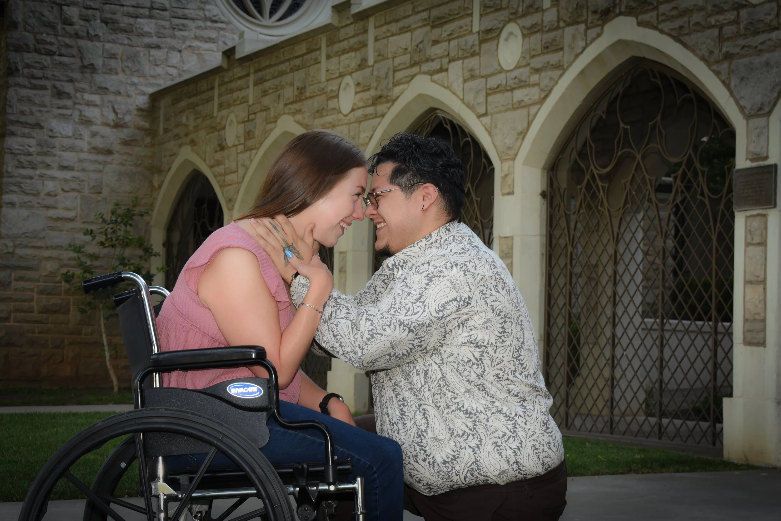 A man and woman sharing a joyful moment with their foreheads touching outside a church.