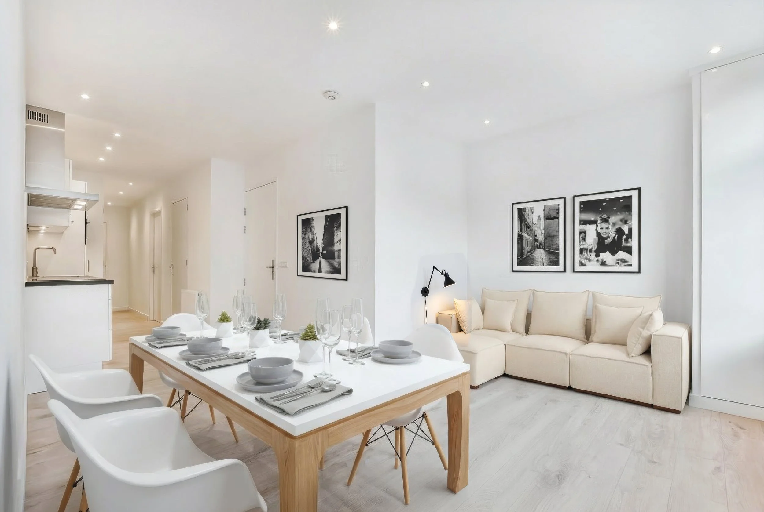 Moderne, helle Wohnung mit Esstisch, weißer Couch, schwarzen und weißen Wandkunstwerken und minimalistischem Dekor.