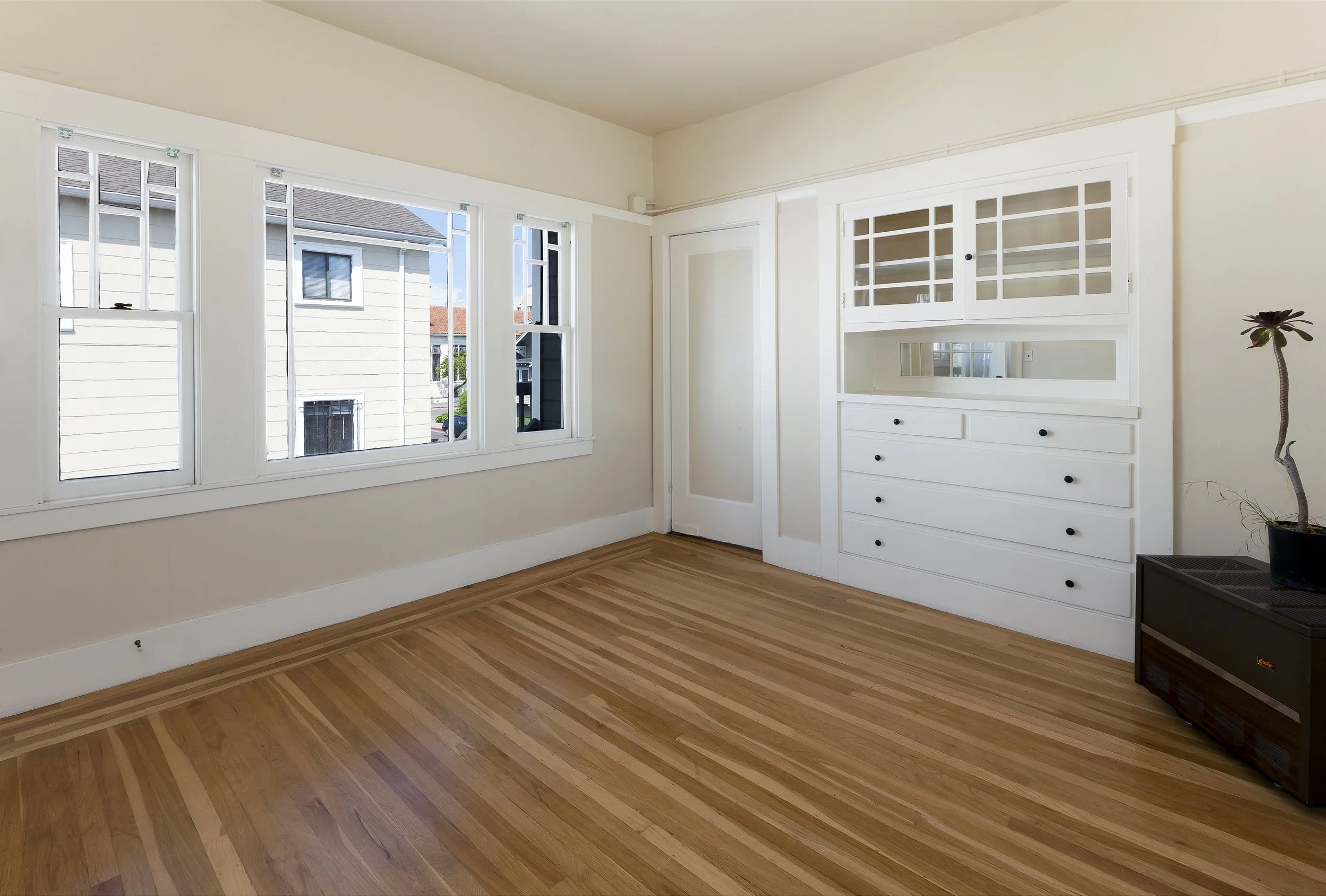 Bright period living room with hardwood floors, built-in cabinetry and tall windows, from Kitt Flood’s listing archive.