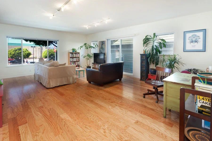 Airy loft living space with hardwood floors, large windows and plants, from Kitt Flood’s listing archive.