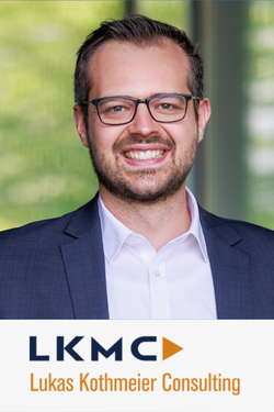 Porträt eines lächelnden Mannes in formellem Anzug mit Brille, Hintergrund mit grünen Bäumen, Logo und Text "LKMC Lukas Kothmeier Consulting".