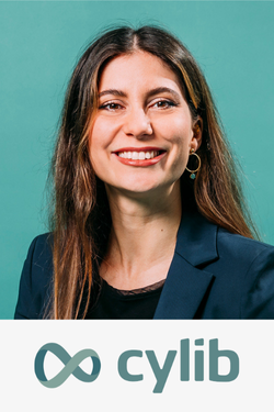 Porträt einer lachenden Frau mit braunen Haaren, trägt einen schwarzen Pullover und eine blaue Blazer, vor grünem Hintergrund, darunter das Logo von Cylib.
