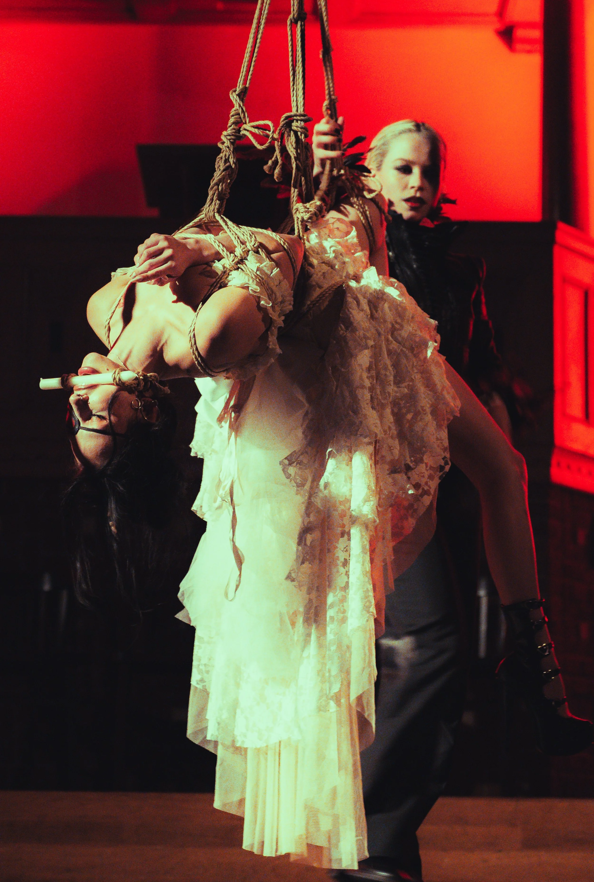 Shibari artist is lighting up a candle in the mouth of her shibari model who has been suspended in rope, japanese bondage. Shibari performance in Amsterdam.