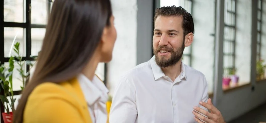 Two small business colleagues having a calm, professional conversation with a leader nearby facilitating the discussion, representing conflict resolution, open communication, trust, teamwork, and healthy workplace culture.