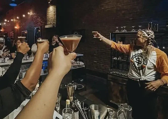 A cocktail class raising their glasses with the instructor at the Standard Proof bar in Nashville
