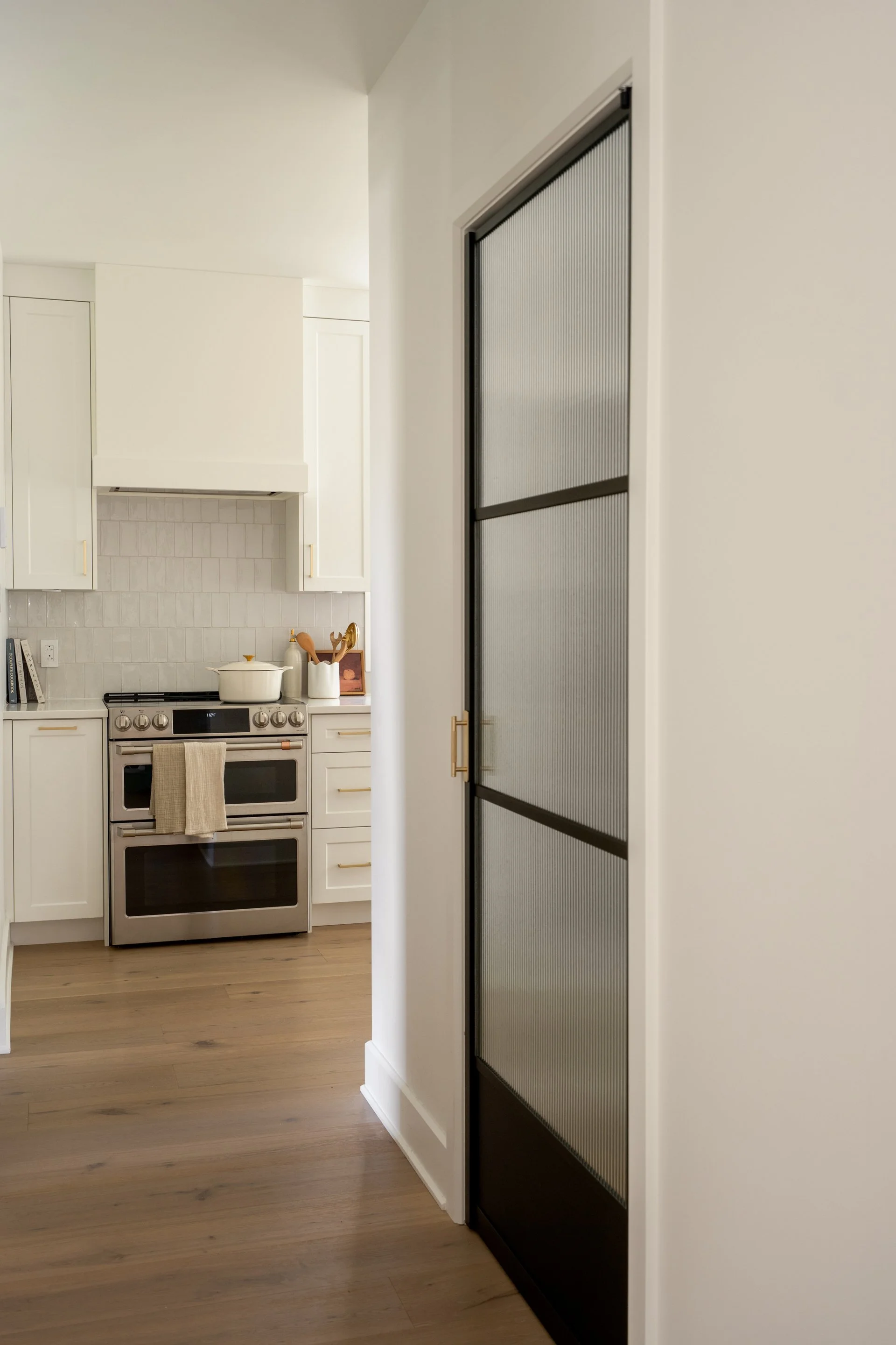 Kitchen with white cabinets, a stove, and a black sliding door with frosted glass panels.