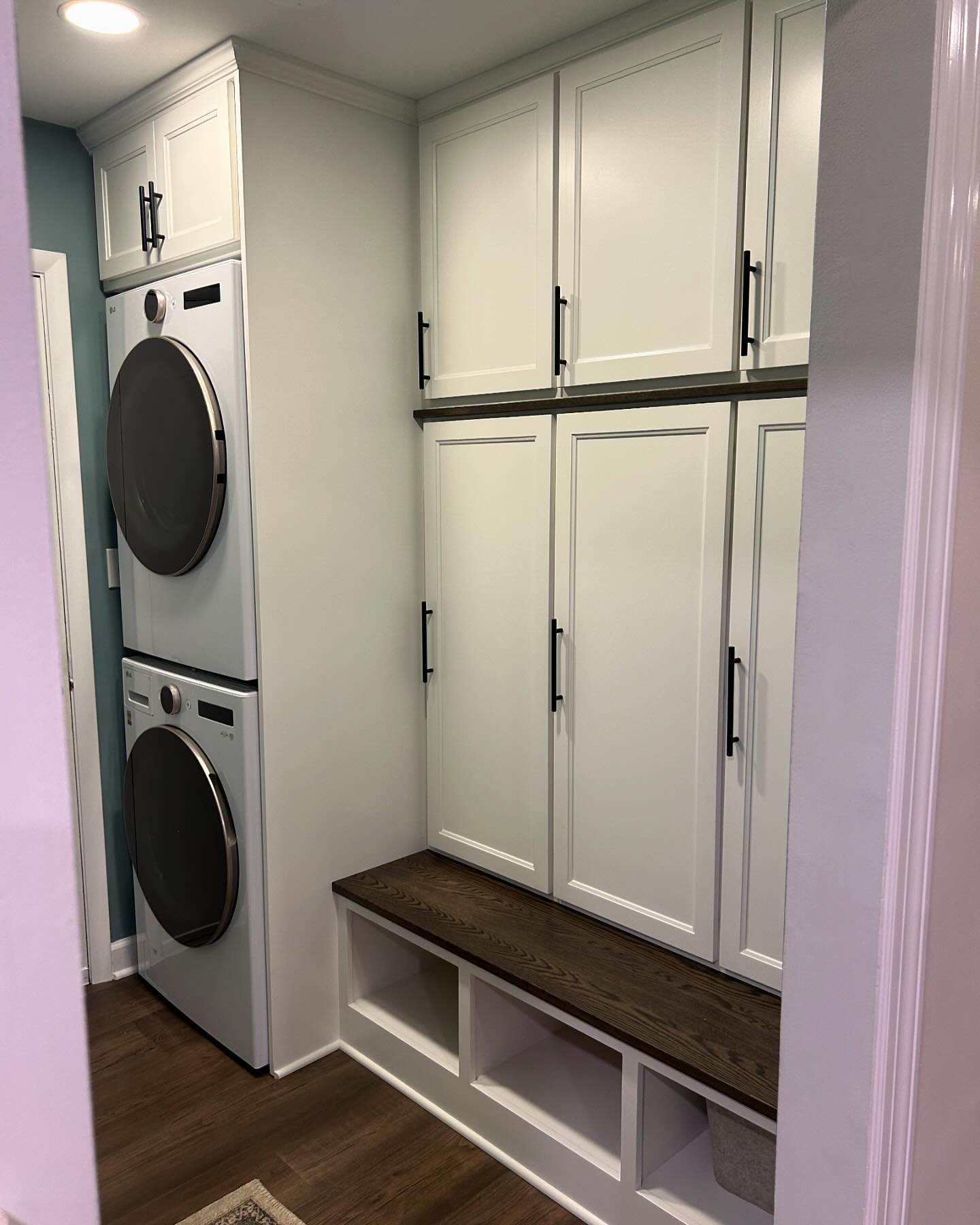 Phase 2 of 2 complete!! Custom Mudroom; bench with cubbies, lockers with hooks, upper cabinets for storage, and over the washer/dryer cabinet for even more storage.  Painted in Alabaster and Red Oak components stained in Ebony to match the Fireplace 