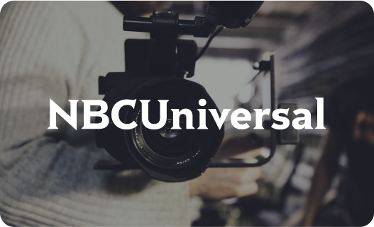 Close-up of professional video camera on a tripod with NBCUniversal logo overlay.