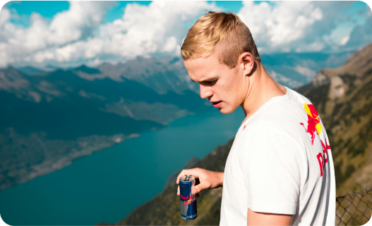 Man standing on a mountain holding a canned drink