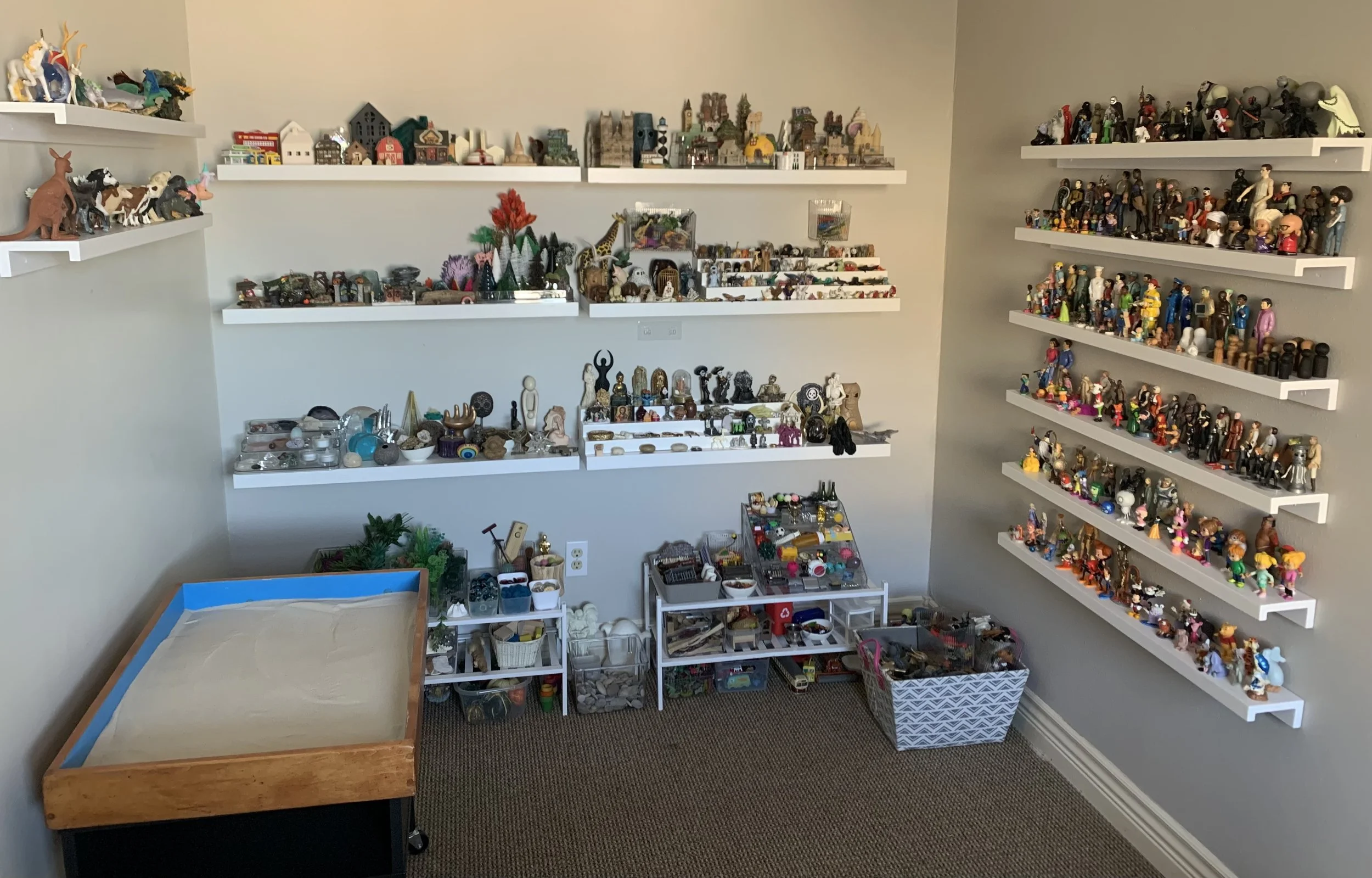Sandtray with shelves of figures in Laura Gambrel's therapy office