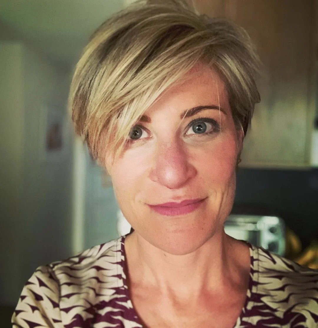 Beth looking at the camera with a calm smile in a burgundy and white patterned shirt