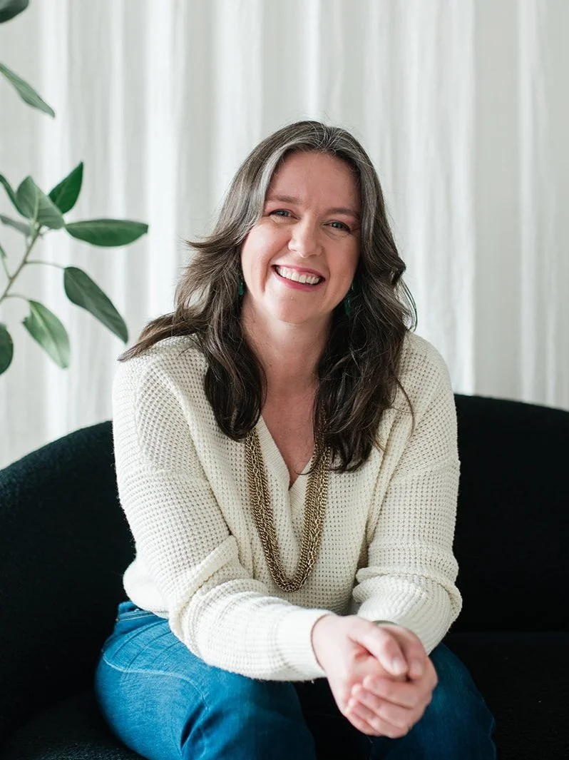 Photo of Rachel Duncan, sitting, hands clasped leaning forward and smiling