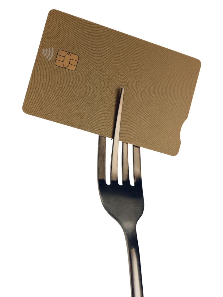 A fork holding a piece of brown cardboard with a chip card and a contactless payment symbol.