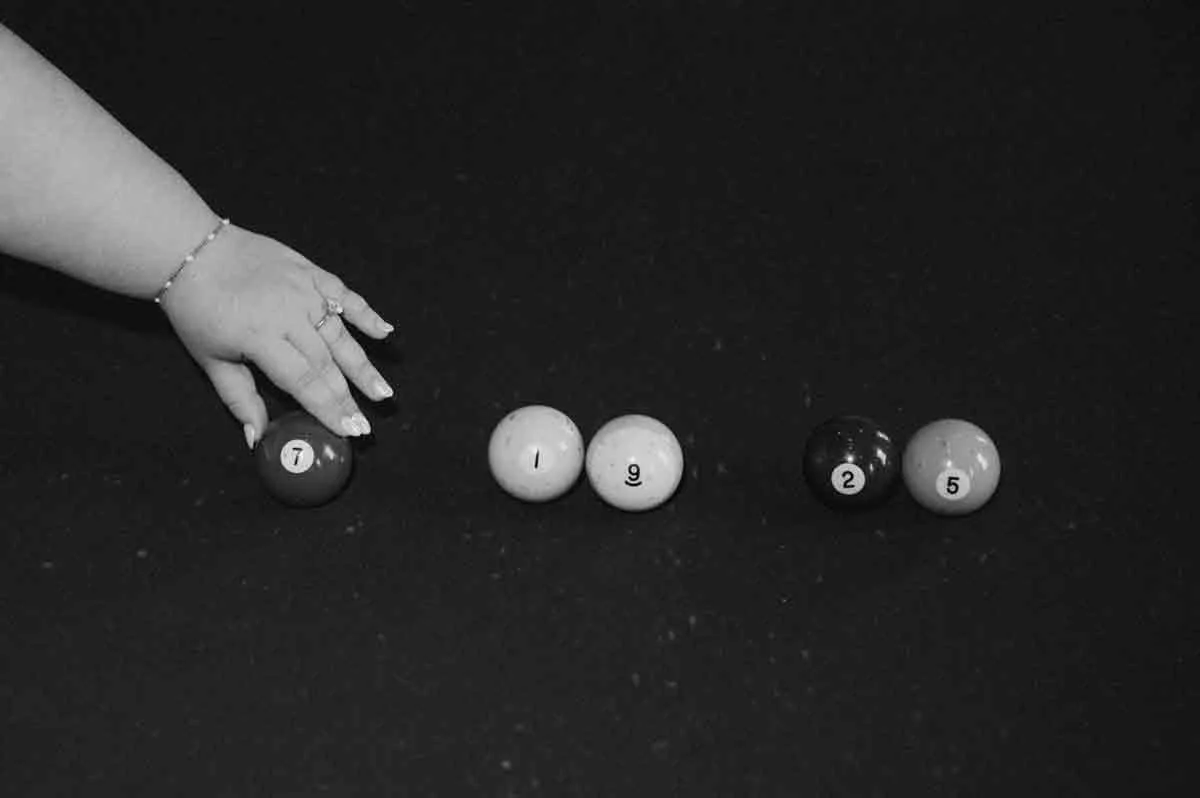 bride grabbing pool ball with wedding date