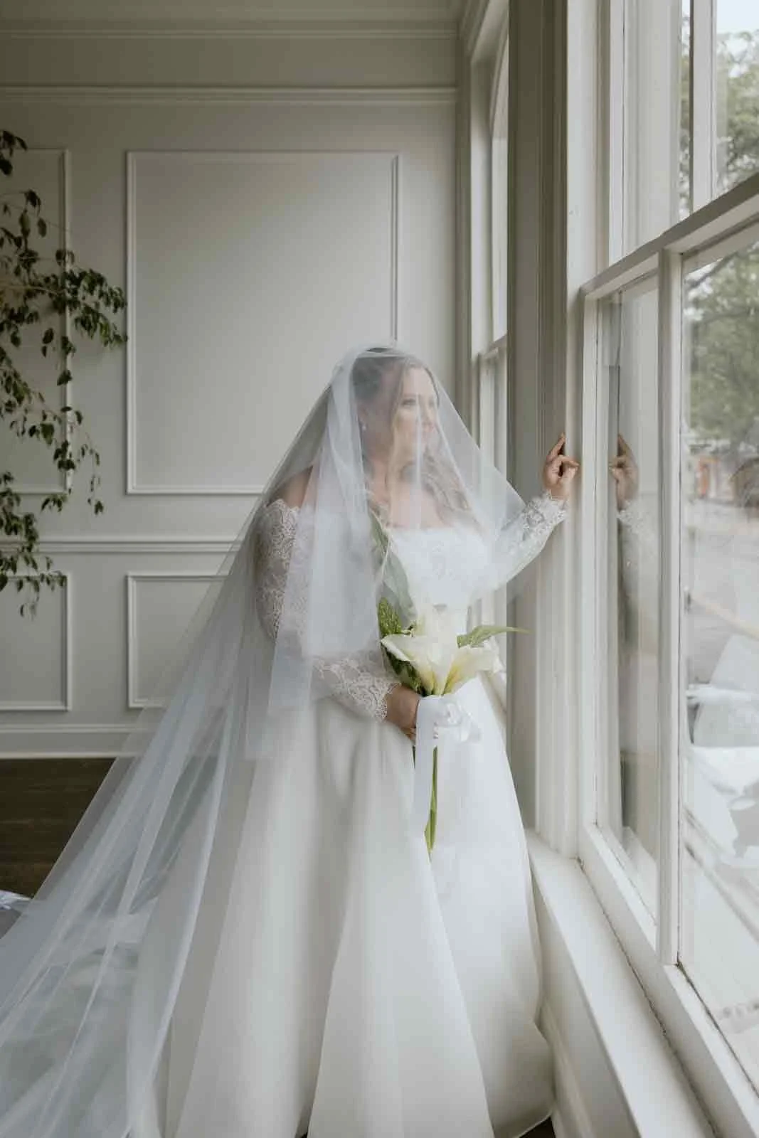 bride looking out window at iron front in Lewisburg