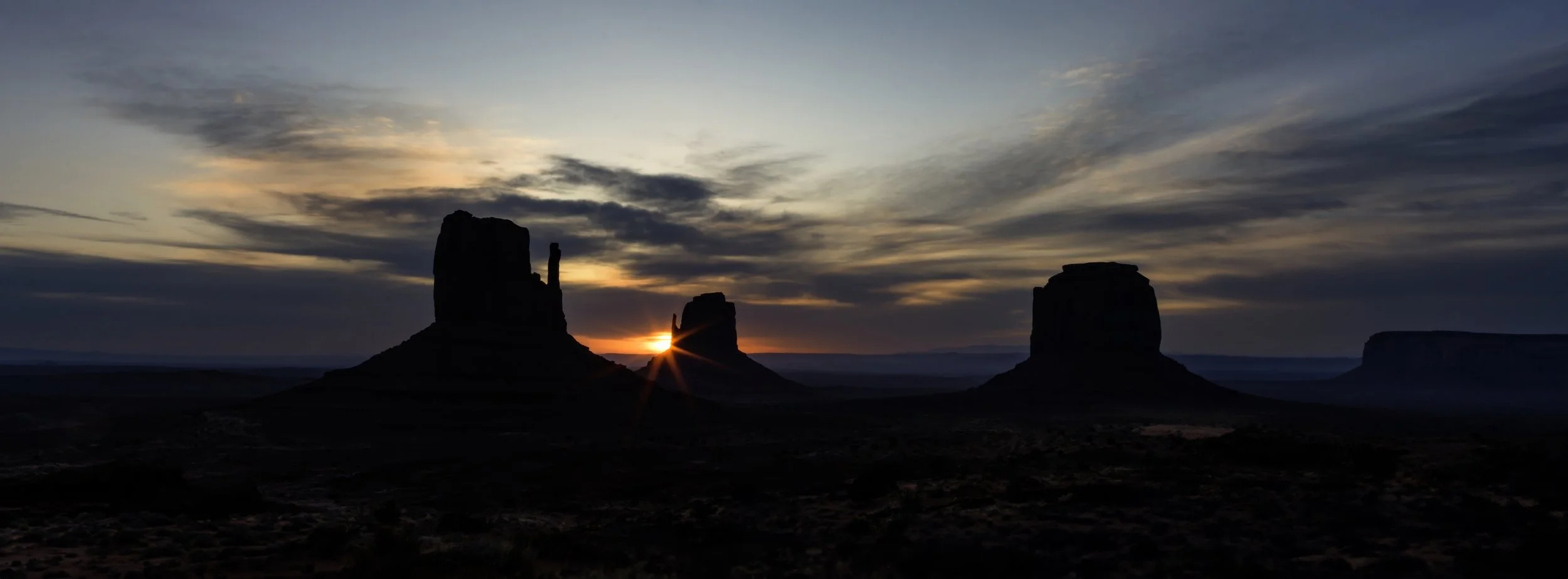 MITTENS IN THE MORNING – The morning breaks behind the West and East Mittens of Monument Valley.