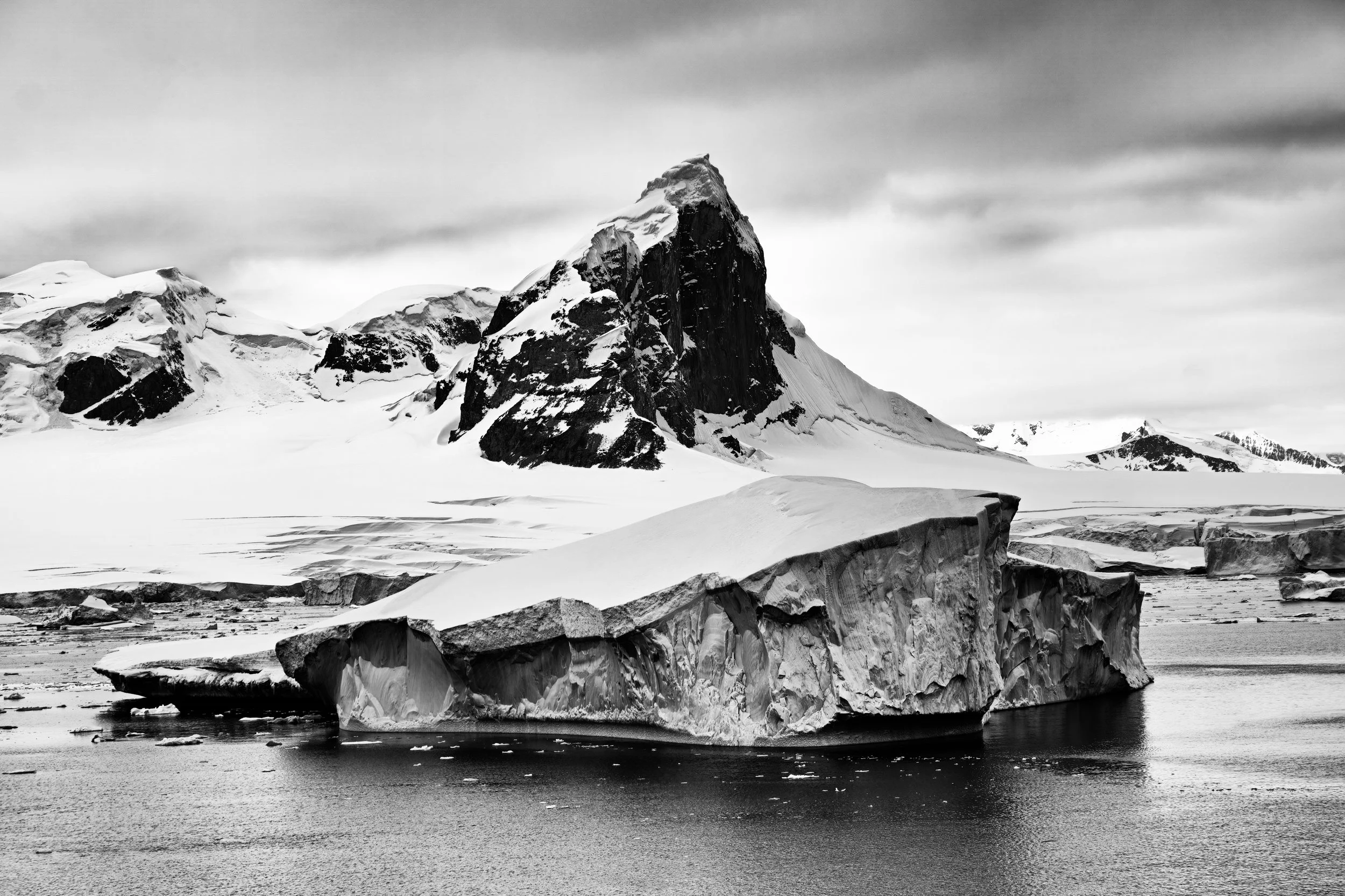 ICEBERG IN NEKO HARBOUR - An iceberg drifts by a arrow-sharp pinnacle along the glaciated Antarctica coastline.