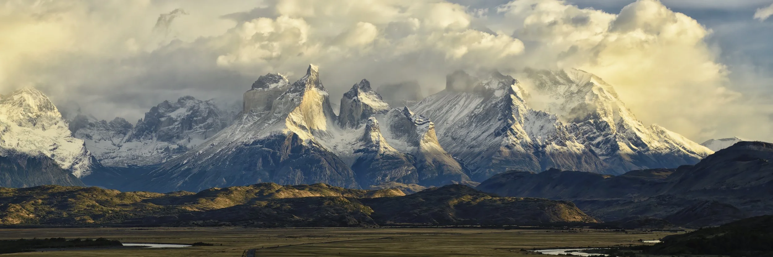 THE PAINE MASSIF – Early morning rays of sunlight striate the Paine Massif in Torres del Paine National Park as clouds build overhead.