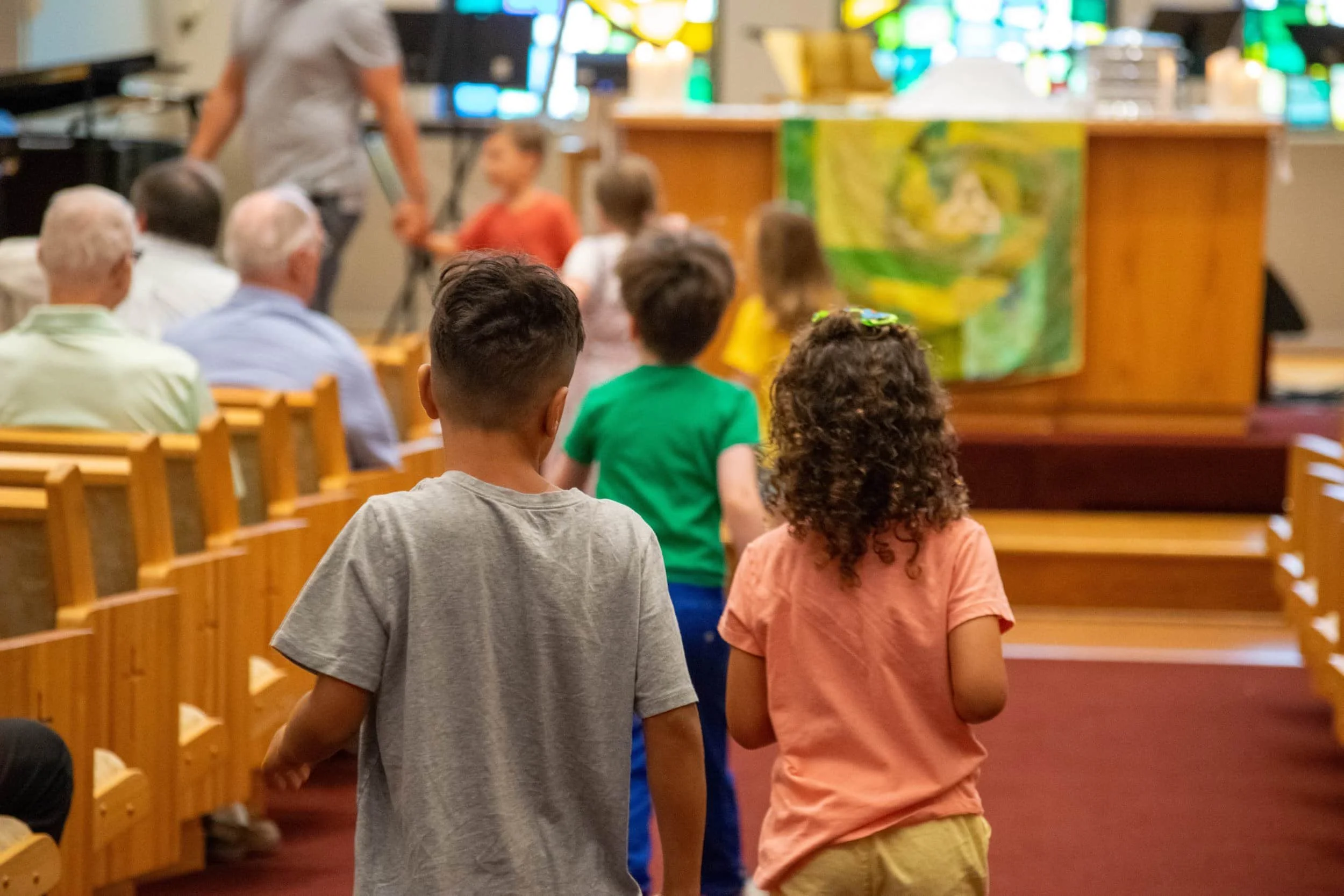 Children walking down the aisle of a church or chapel during a religious service or event.