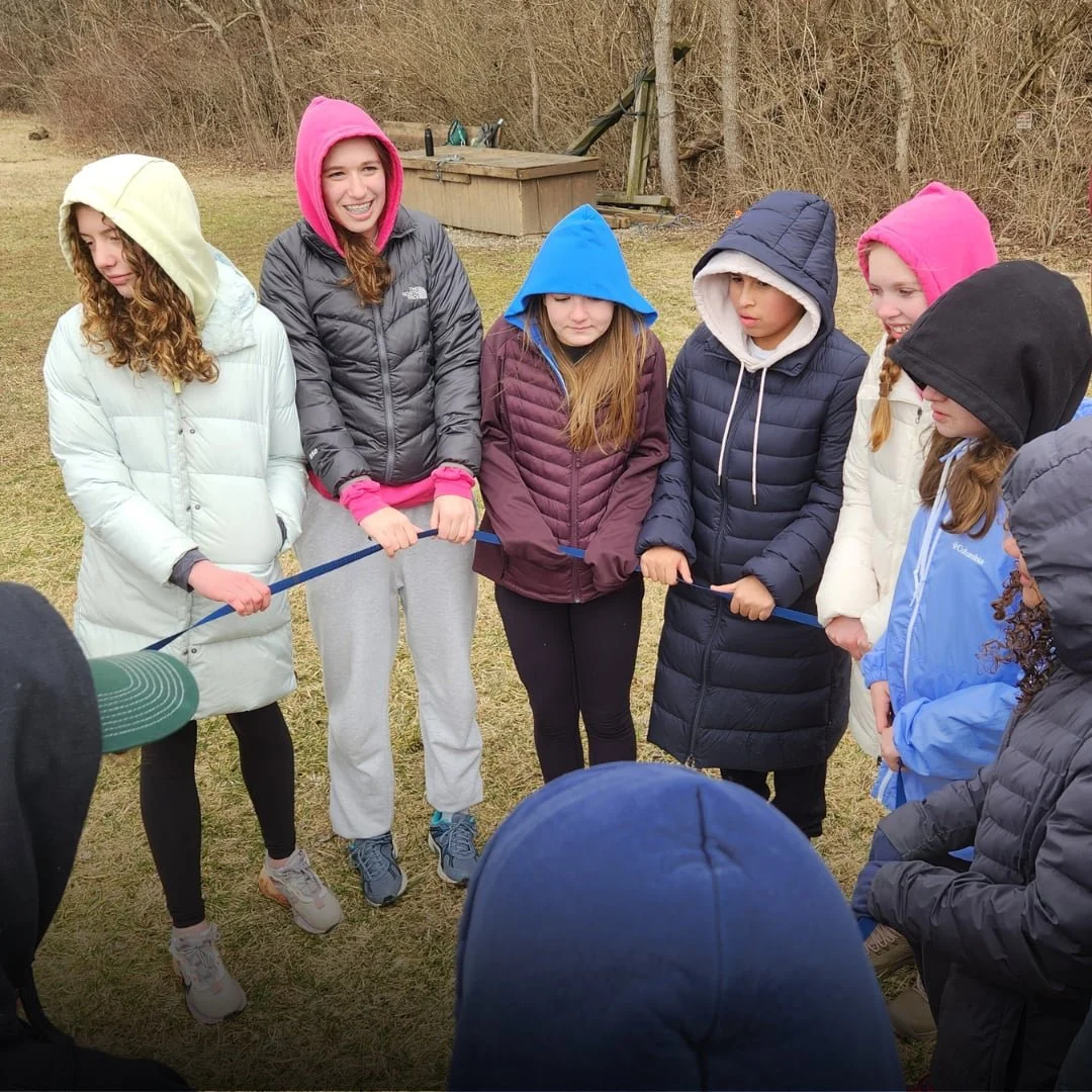 Students participating in an outdoor team building activity at a retreat at a camp.