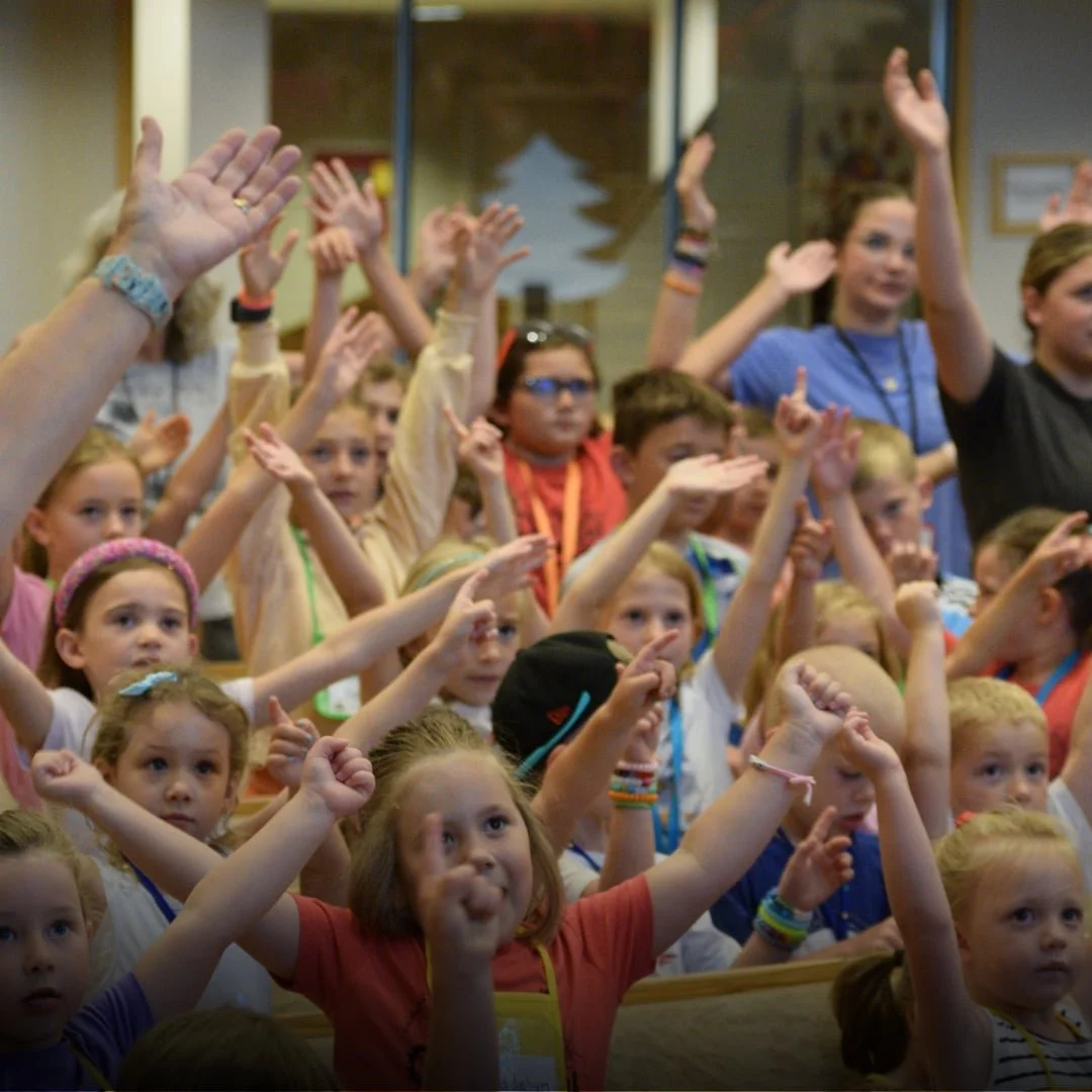 Group of children raising their hands during a classroom activity.