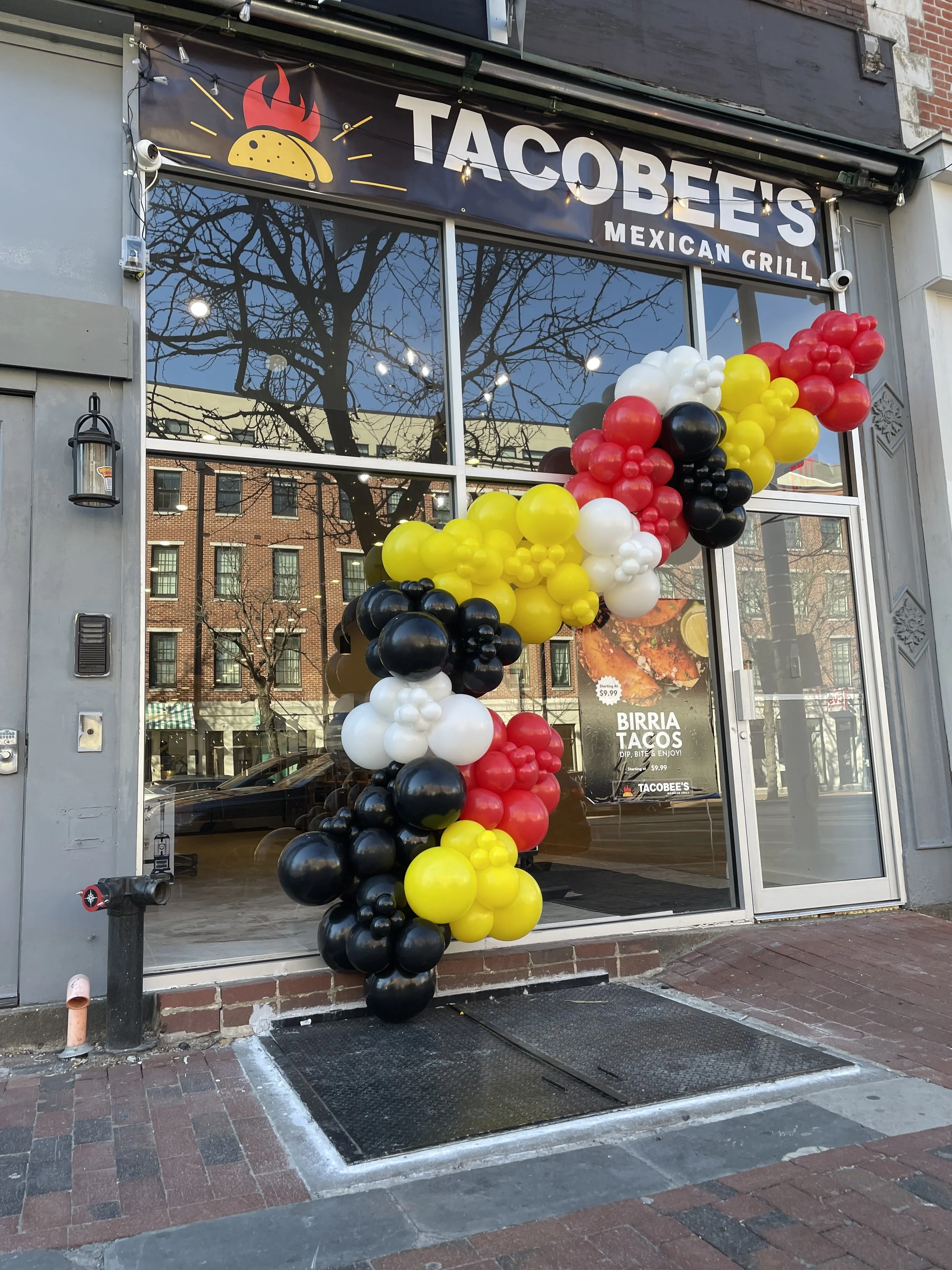  storefront for TacosBee's Mexican Grill decorated with colorful balloons in black, white, red, yellow, and brown.
