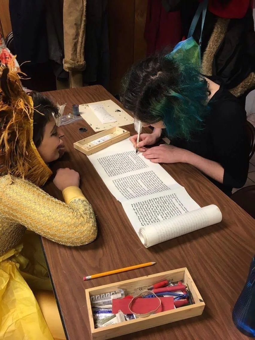 community member helps complete a letter for a Megilat Esther on Purim