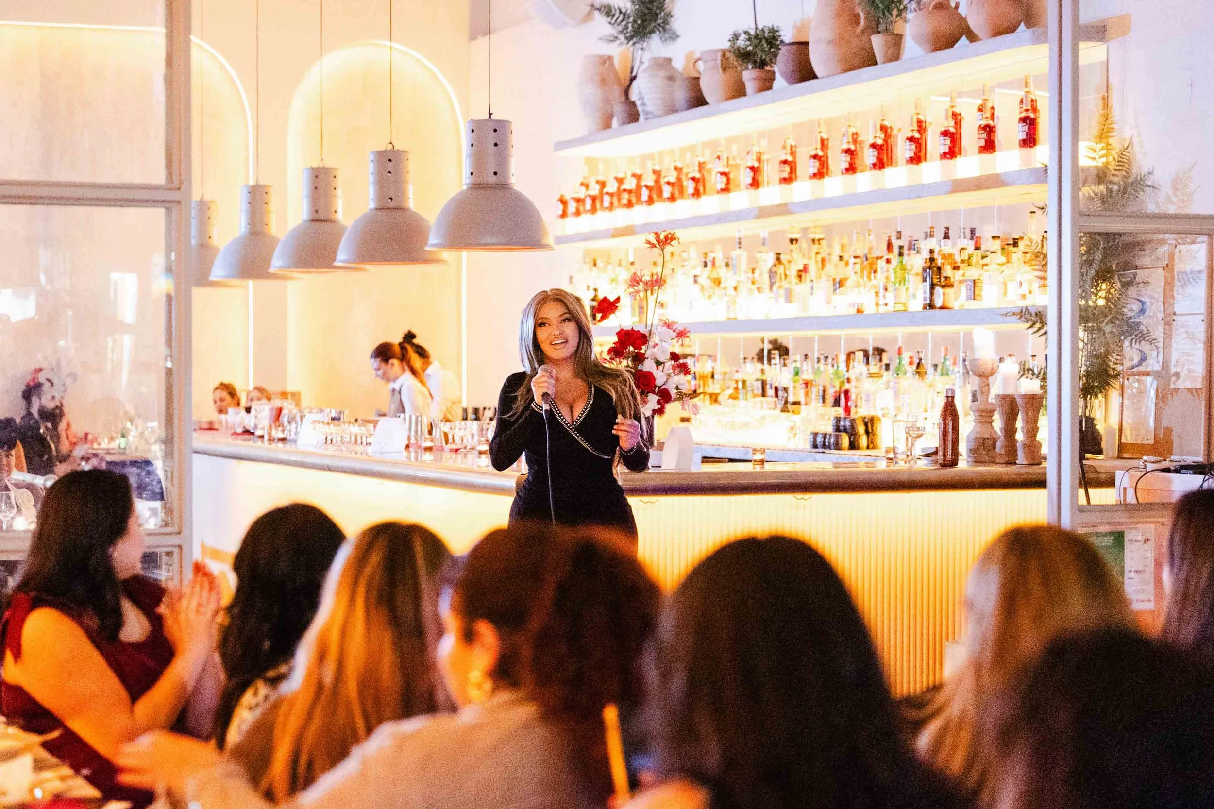 Latinas in Beauty founder speaks from the bar at Negroni Beverly Hills during the non-profit's launch event, photographed by a Los Angeles event photographer.
