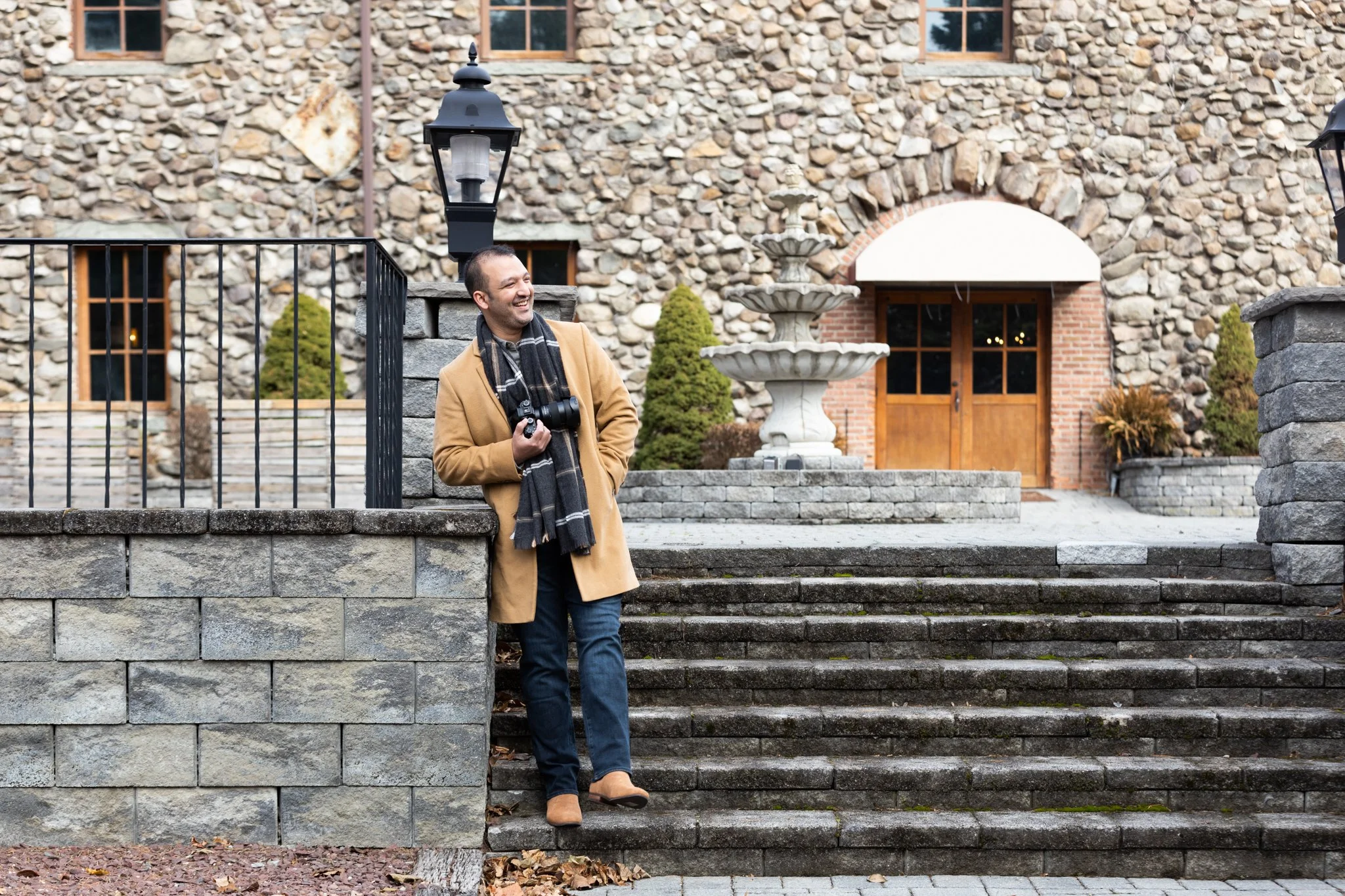 A NJ brand portrait photo of a man standing in front of a stone building.