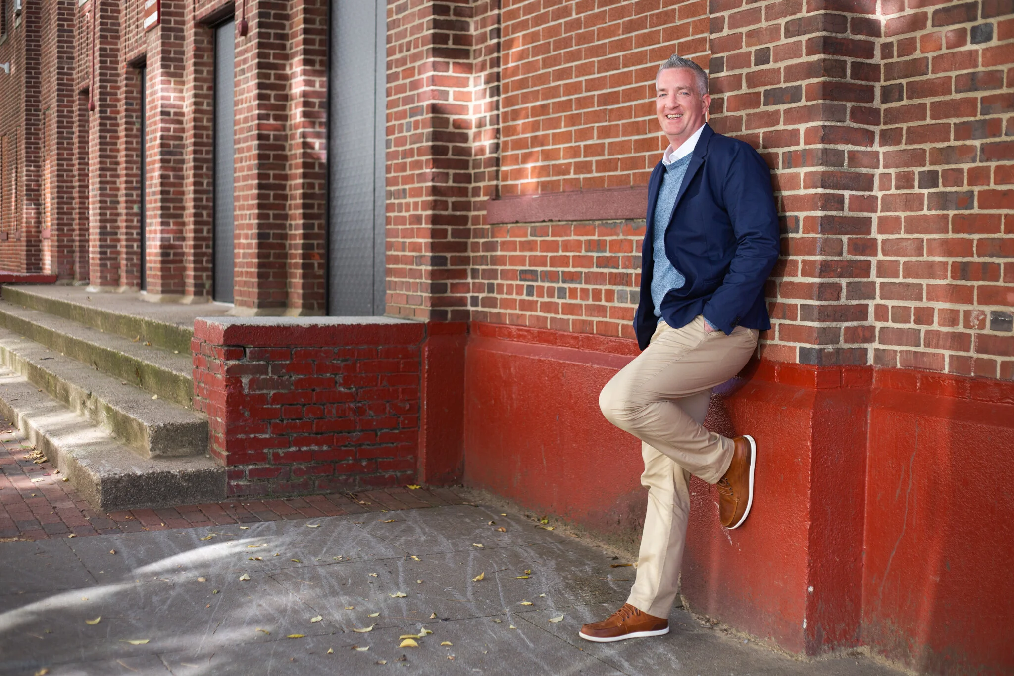 A man stands in front of a school in Jersey City in this NJ brand photography session