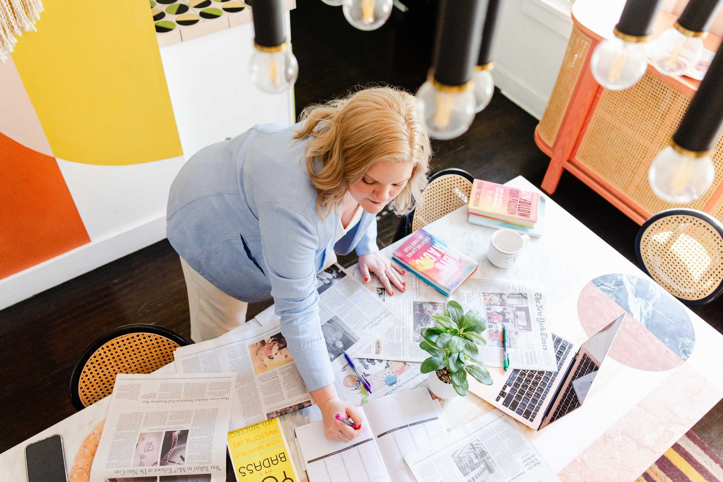 Flatlay of a creative entrepreneur planning a brand photoshoot with printed mood board, planner, props, and workspace items