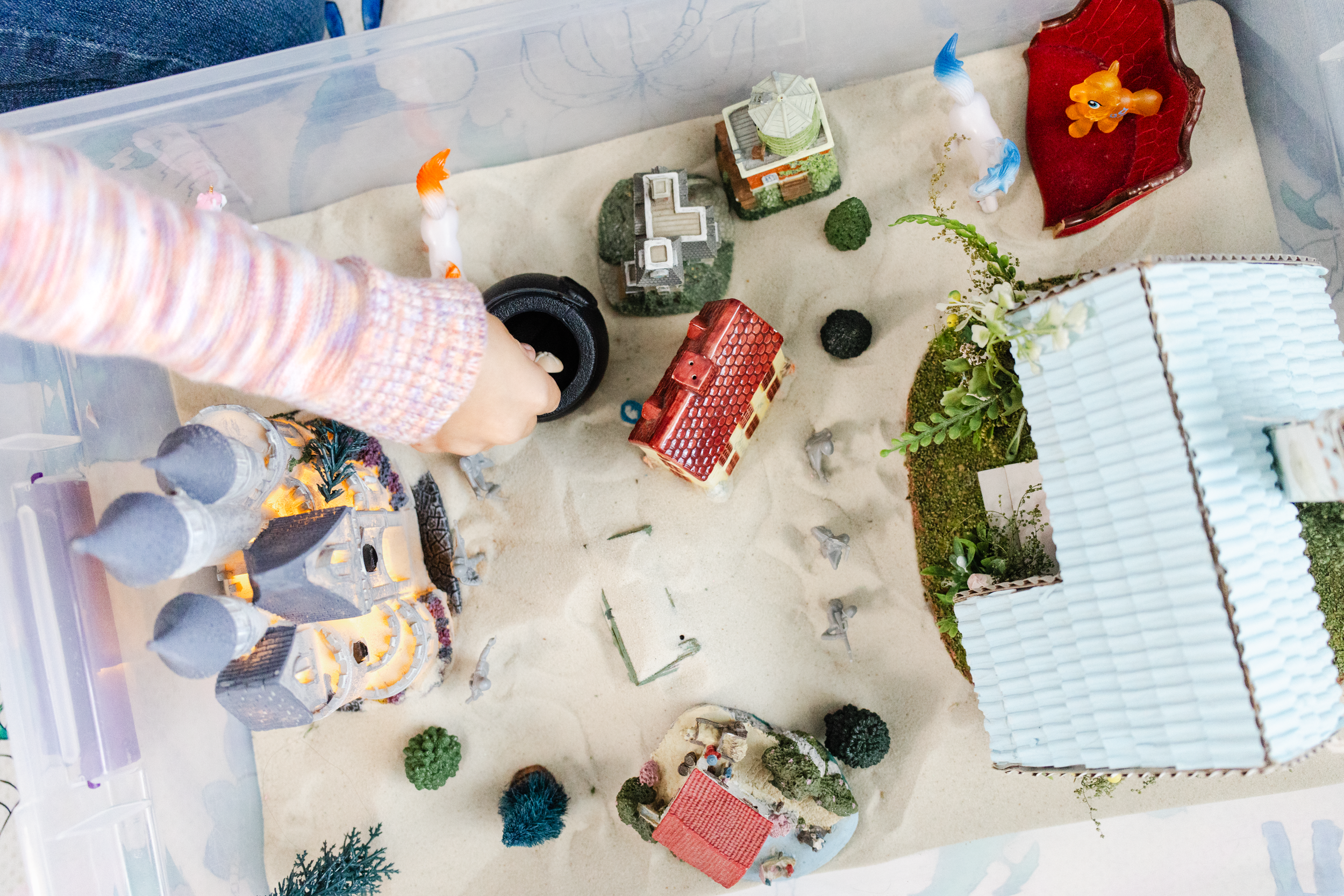 A child's hands reach into a sandbox with toys during a brand photo session for an LMFT.