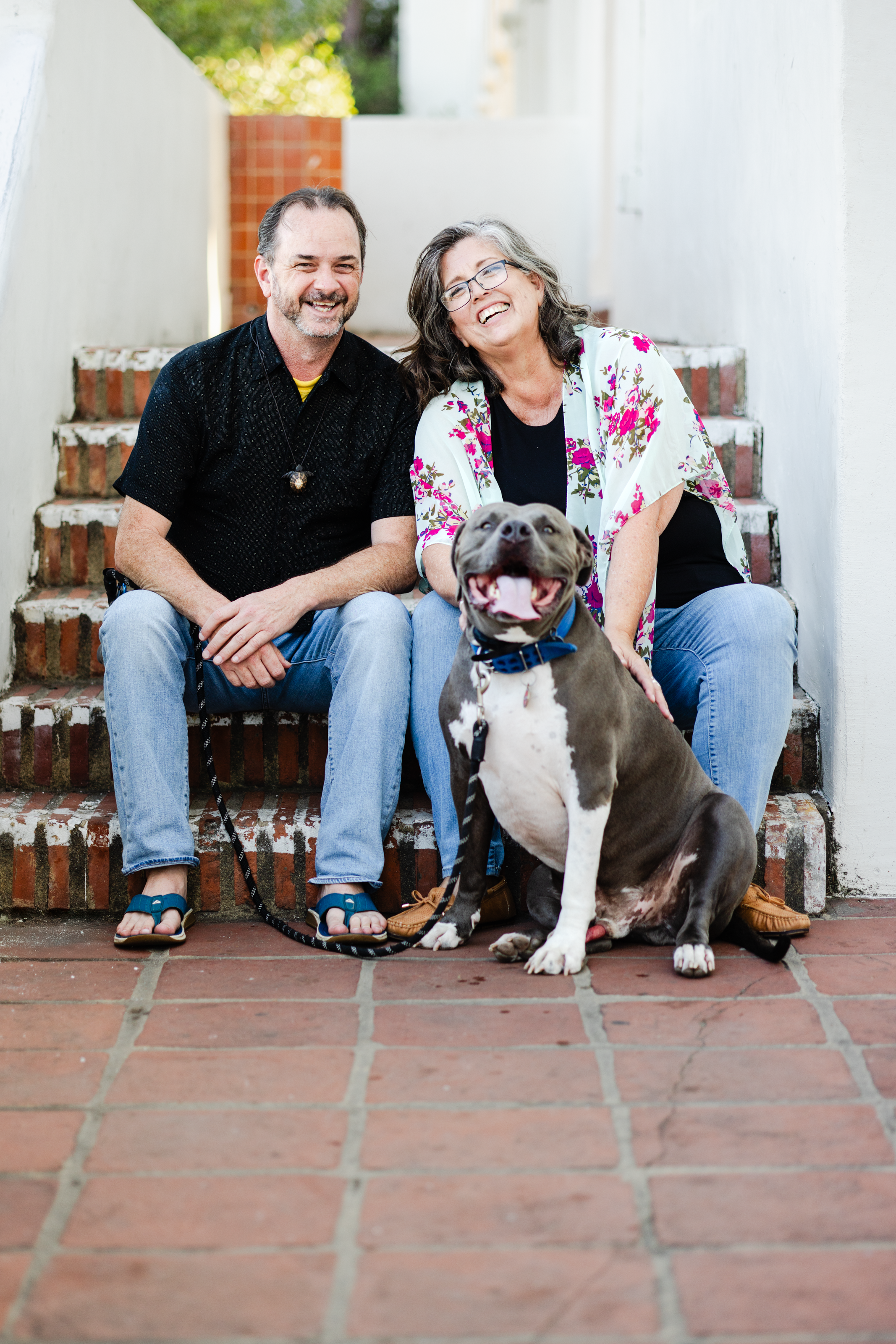 A family portrait of an LMFT, her partner, and her dog sitting on steps for her therapy business's brand photo session.