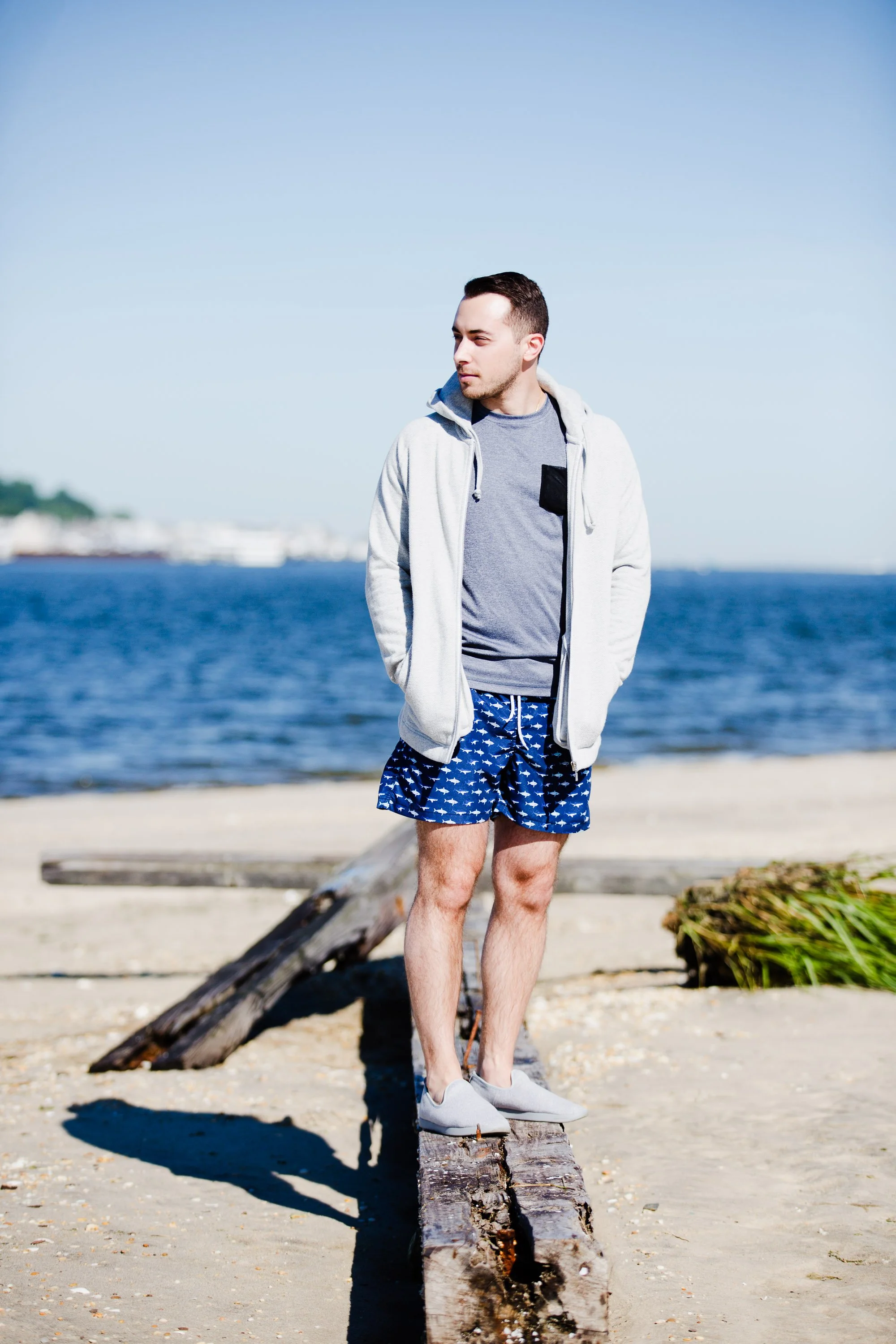 Man posing by the ocean at Sandy Hook, New Jersey, during a beach brand photo shoot with relaxed, summer vibes