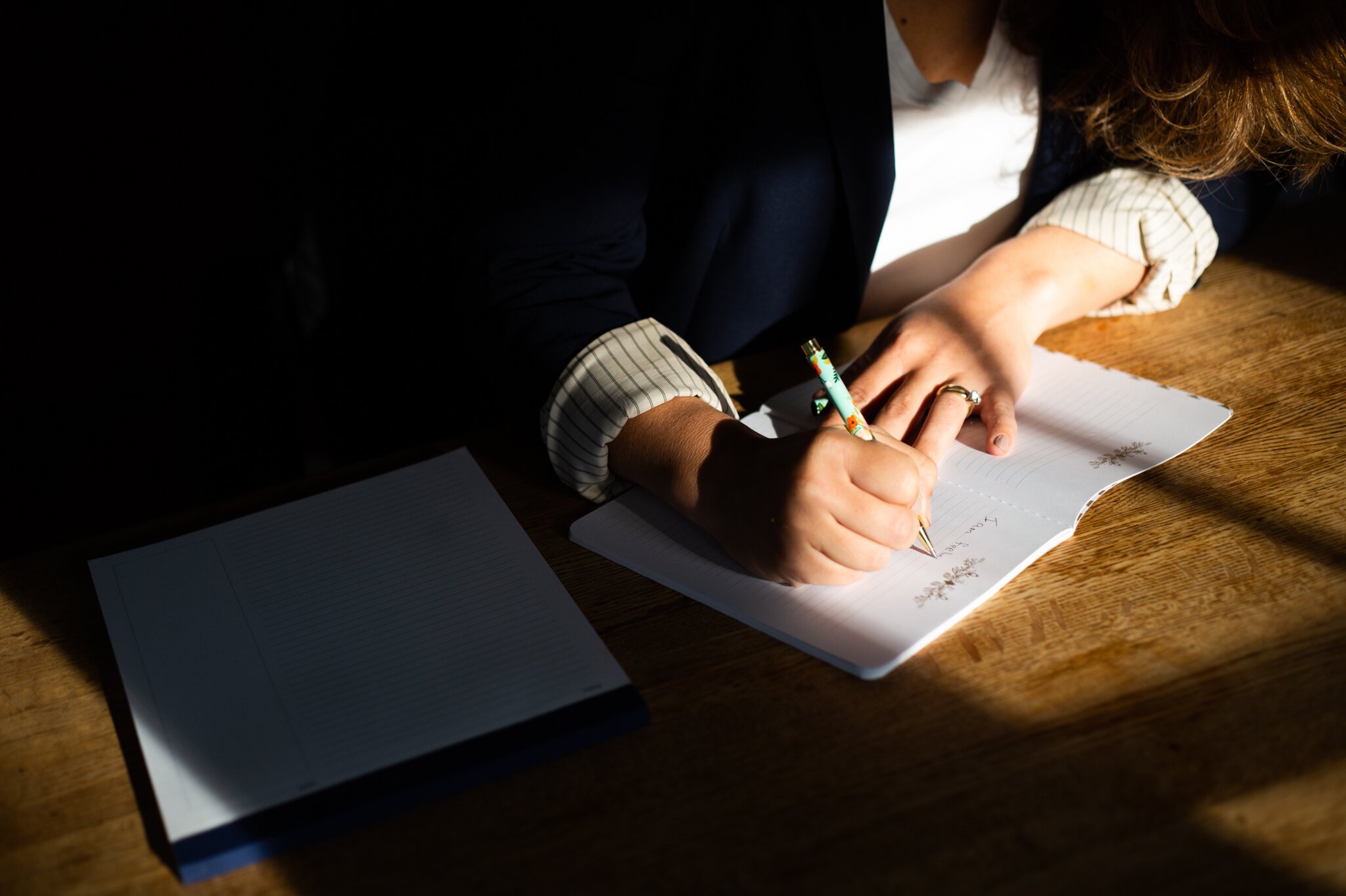 A woman's hands are seen writing on notebook paper in this New Jersey brand photo of coach Amy Young