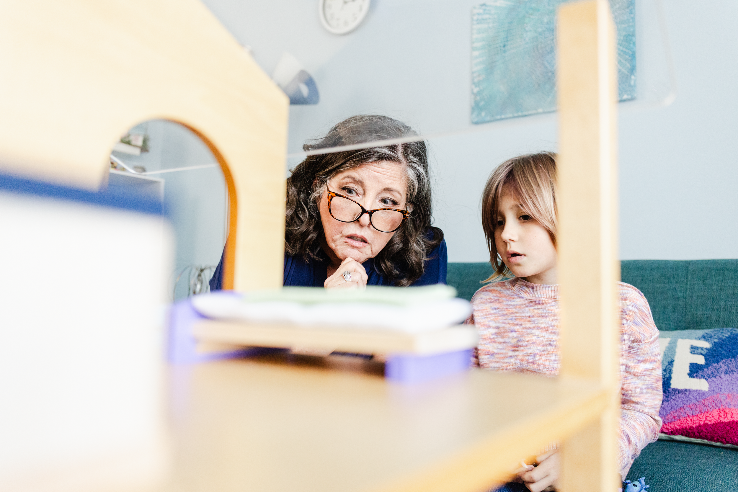 A therapist and her child client play with a wooden house during a mock session for a brand photography photo shoot.