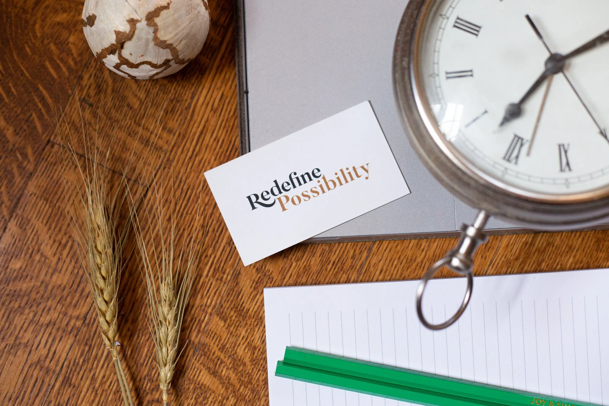A flat lay photo of a business card, laptop, pencils, notebook paper, and decorative straw for Amy Young during her New Jersey brand photography session