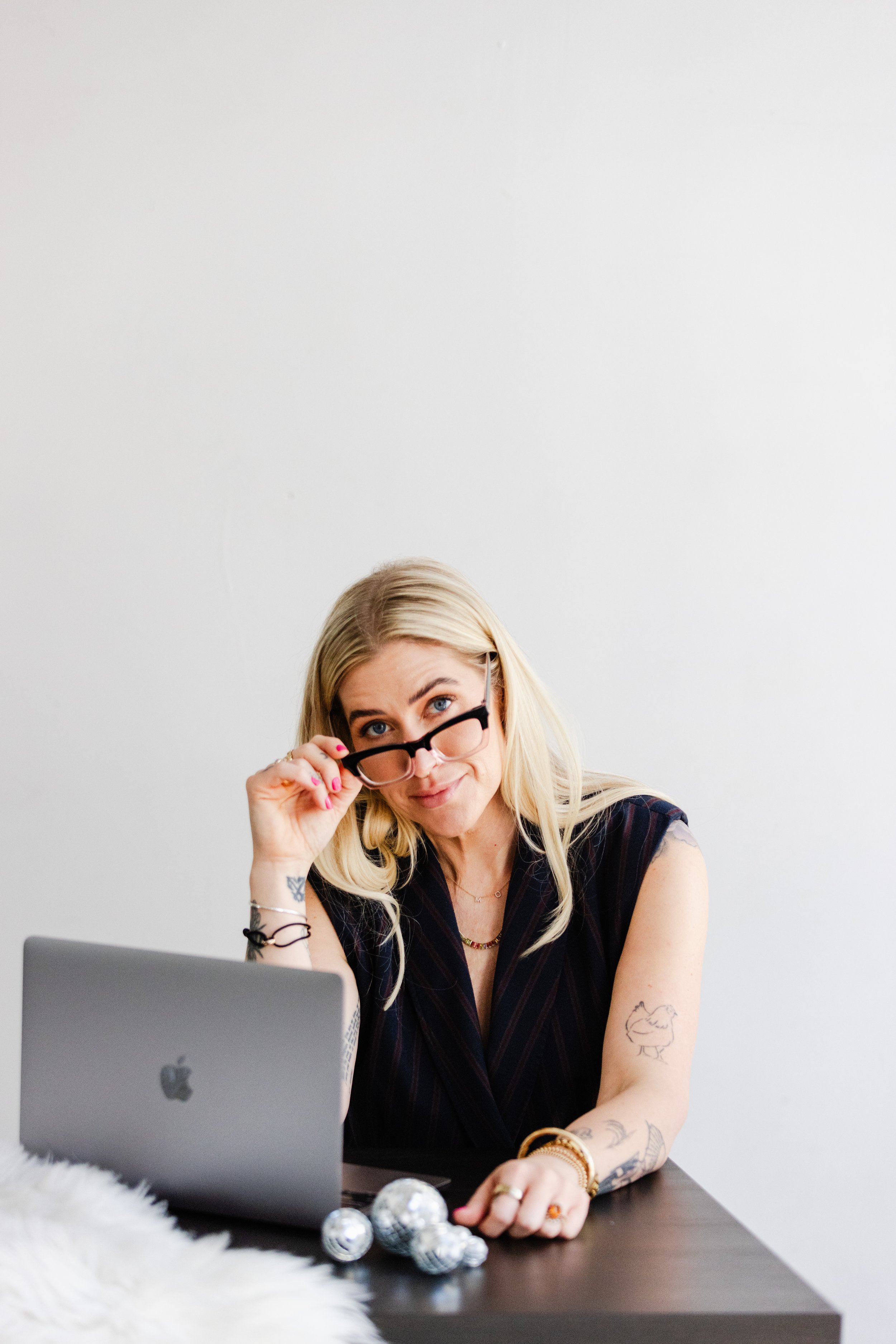 Business coach adjusting her glasses while sitting at her laptop, surrounded by mini disco balls, during a creative brand session in downtown LA.
