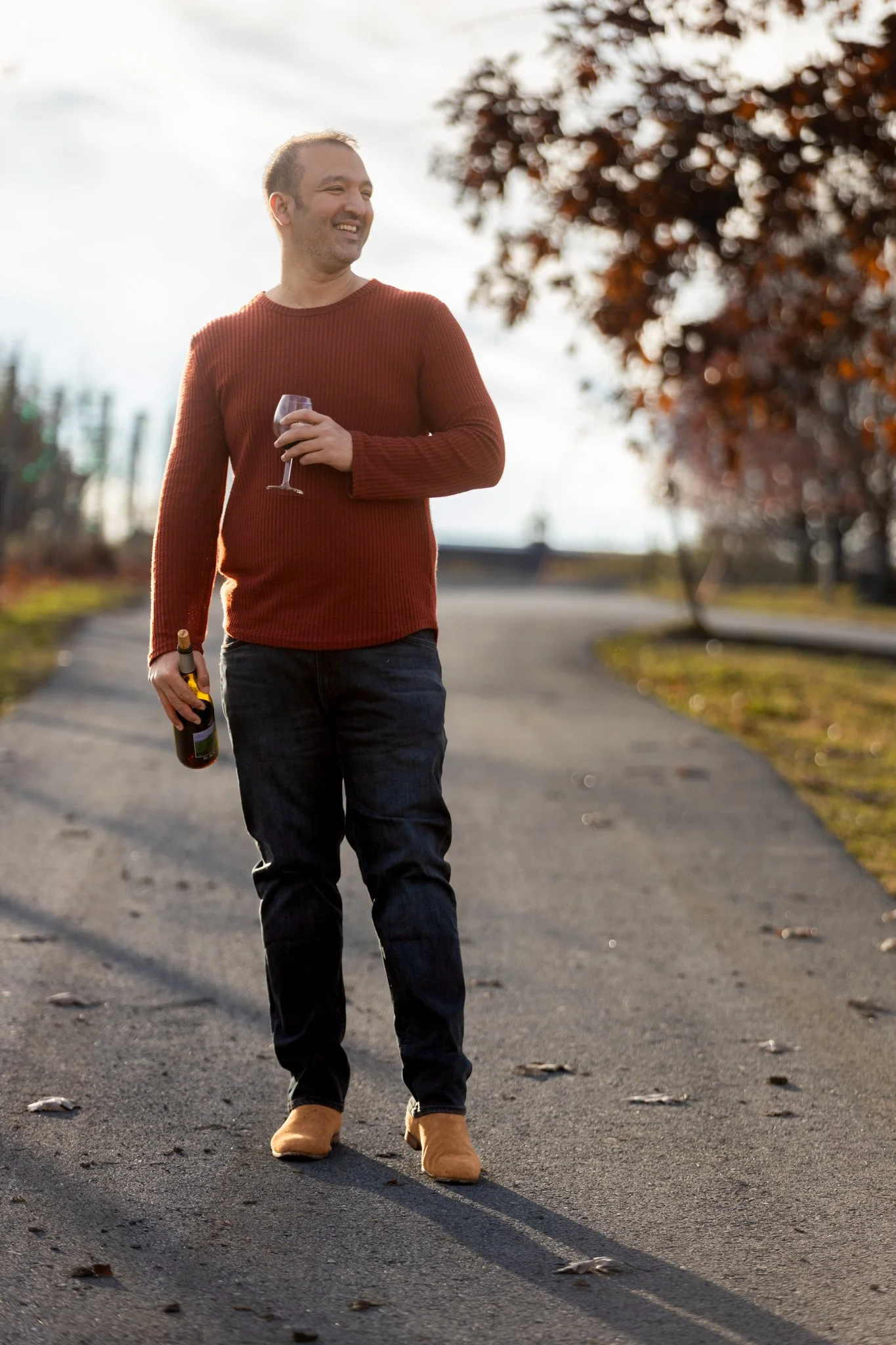 A male holds a bottle of wine in one hand and a glass of wine in another in this NJ branding photography session.