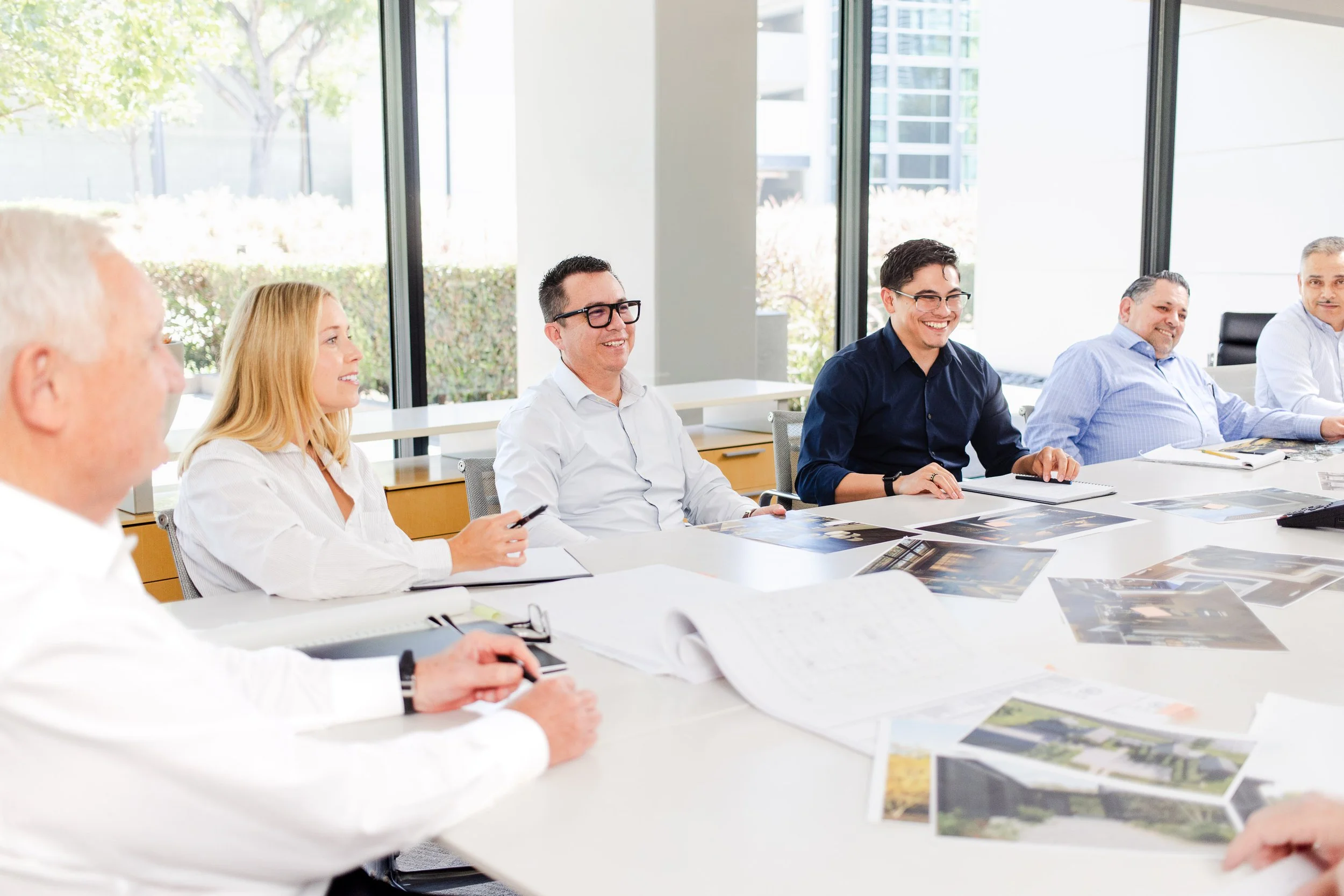 Robert Hidey Architects staff share a relaxed group conversation during a collaborative meeting in their office.