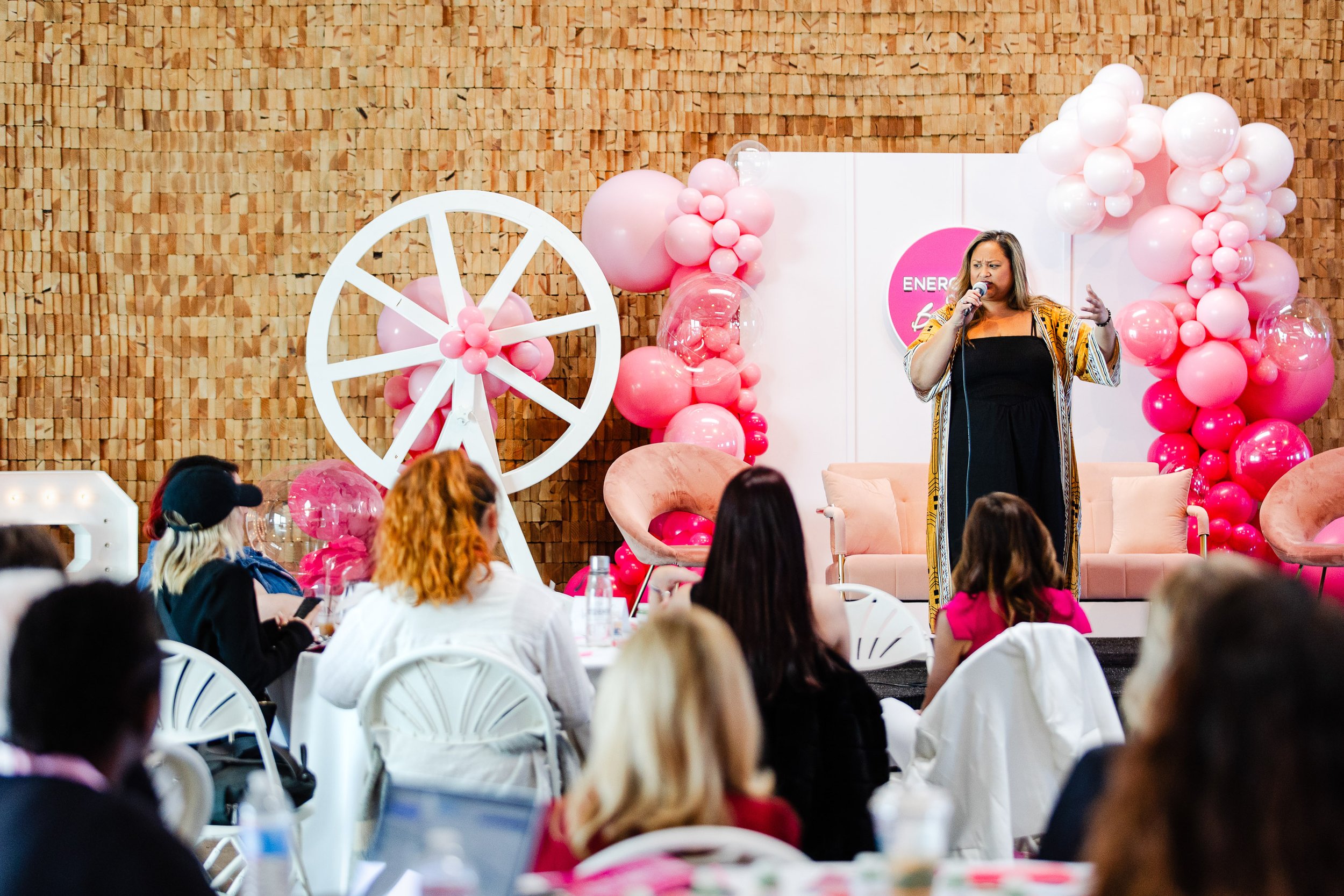Wide shot of female keynote speaker presenting at Energetics of Business event