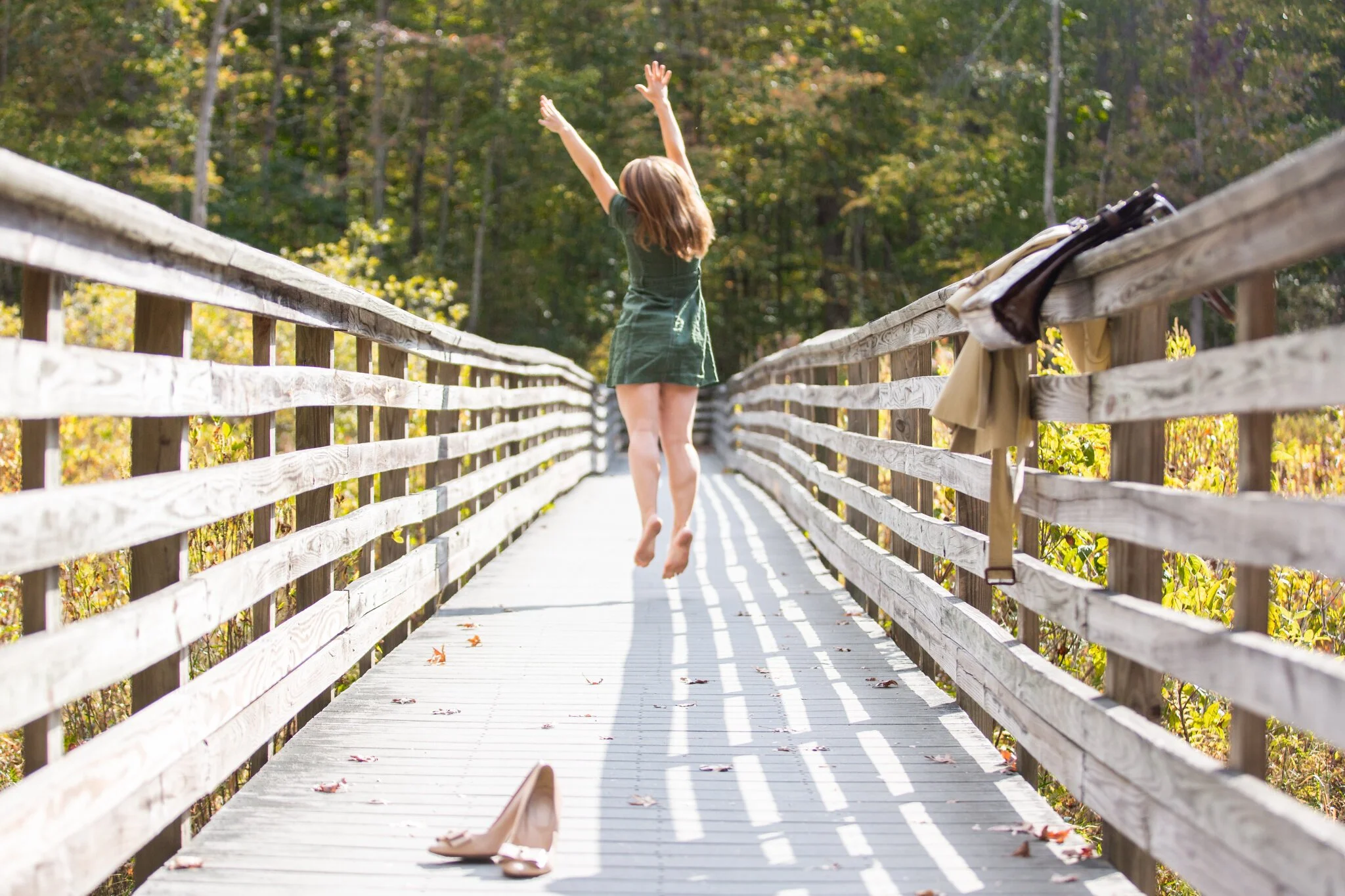 Woman walking across wooden footbridge at Great Swamp National Wildlife Refuge during a New Jersey brand photography session