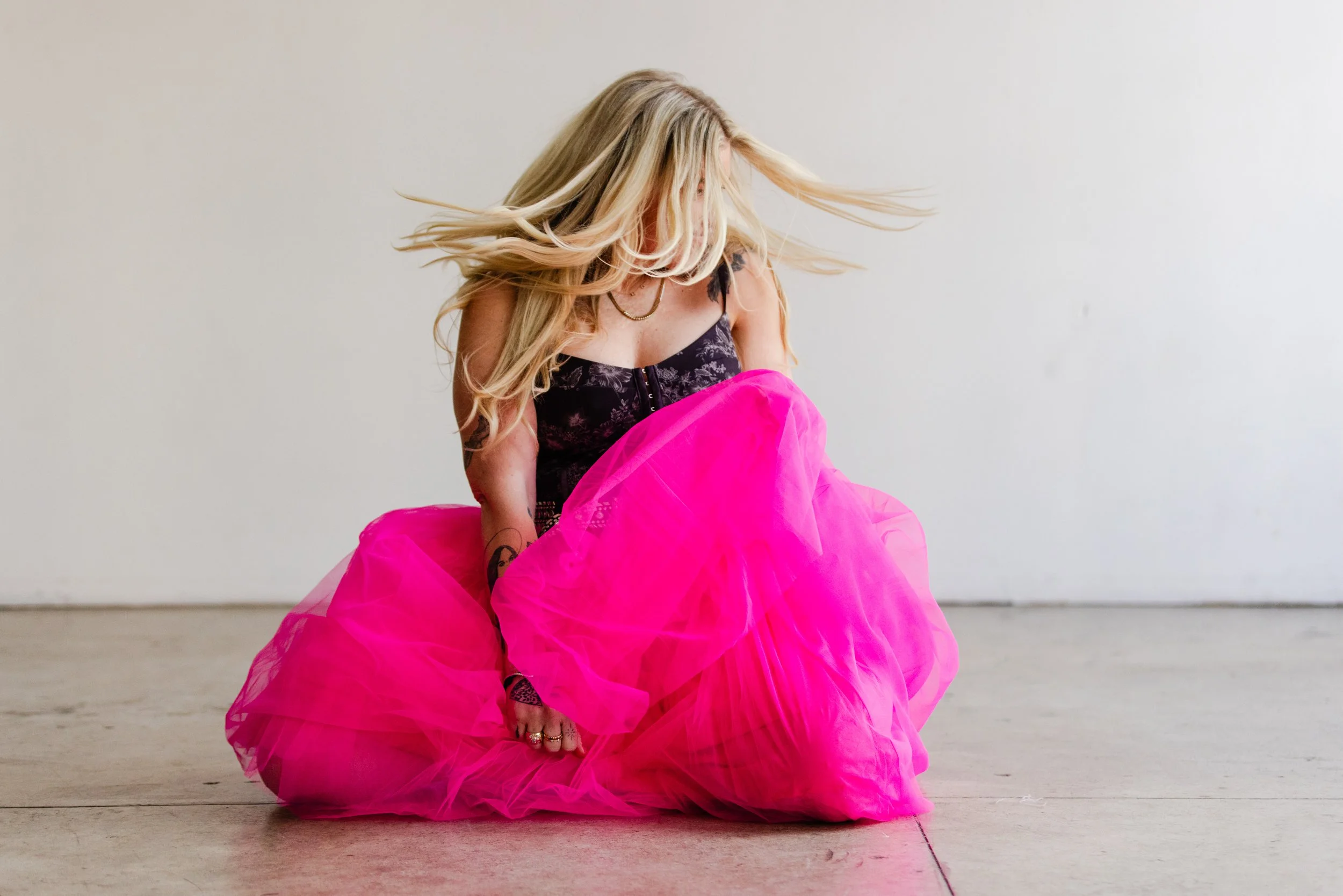 Bold brand portrait of a business coach twirling in a dramatic hot pink tulle skirt during her LA brand photoshoot, full of energy and motion.